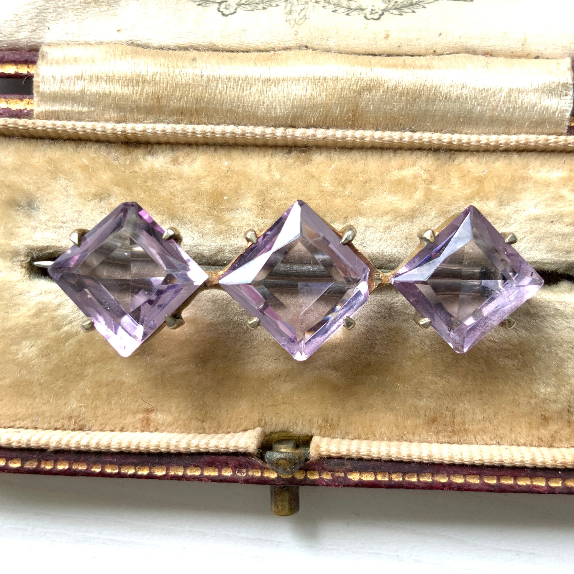A silver bar brooch featuring a row of beautiful, translucent lavender-coloured diamond-shaped amethysts.  透明感のある美しいラベンダーカラーのダイヤ型アメジストが並んだシルバーのバーブローチ。