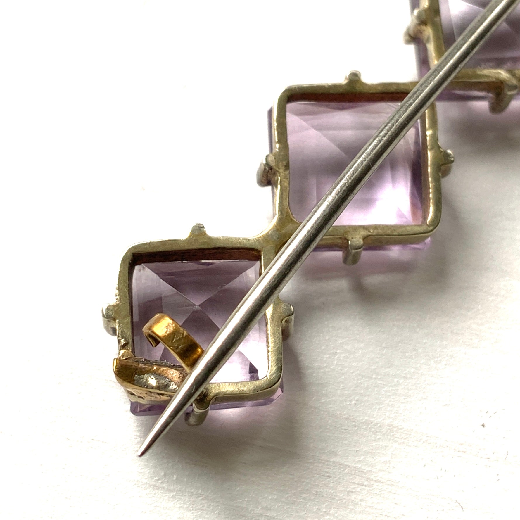 A silver bar brooch featuring a row of beautiful, translucent lavender-coloured diamond-shaped amethysts.  透明感のある美しいラベンダーカラーのダイヤ型アメジストが並んだシルバーのバーブローチ。