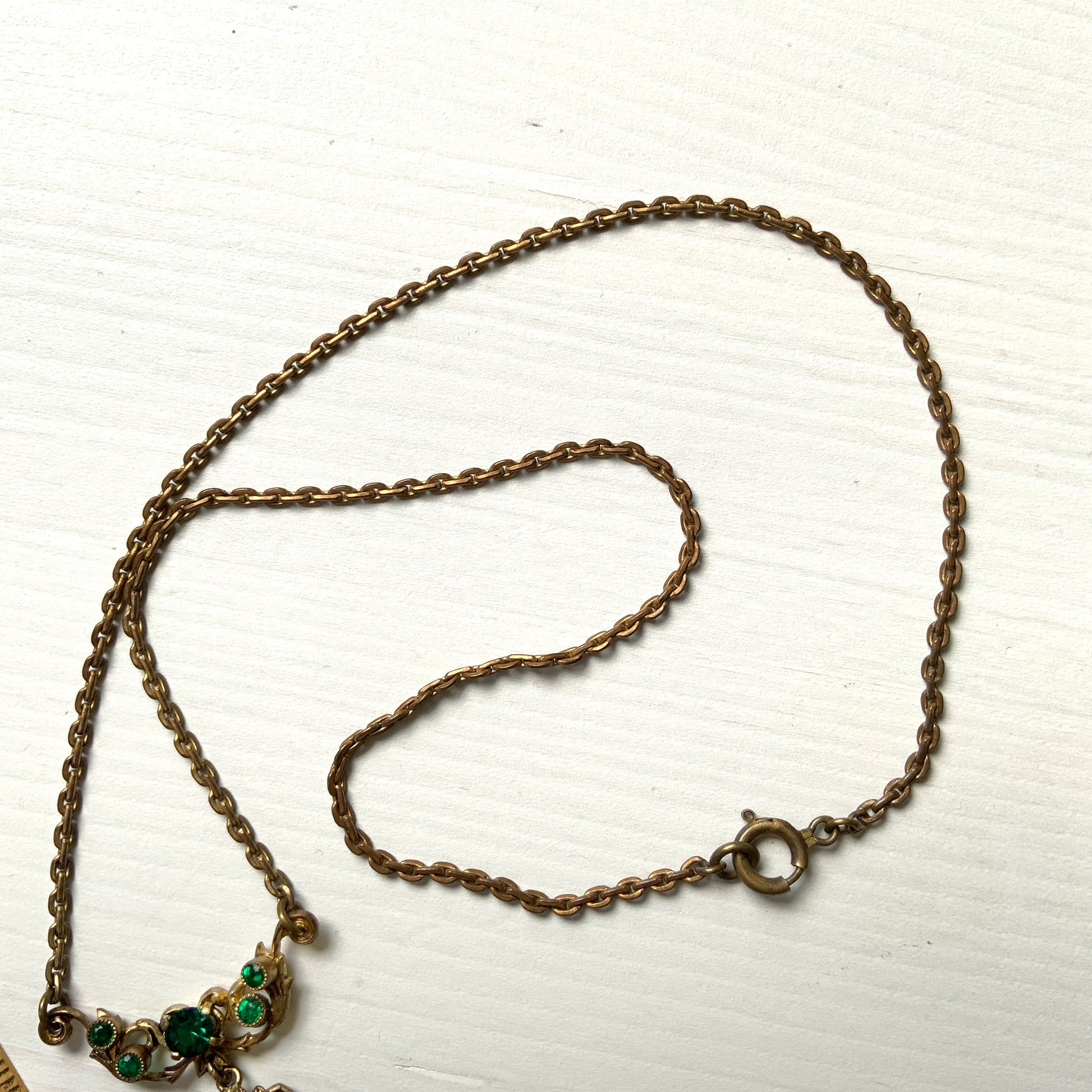 This necklace features a beautiful gold-tone teardrop hoop filigree, adorned with green, purple, and white stones in the colours of the suffragette movement.  美しいゴールドトーンのティアドロップフープ のフィリグリーに、緑、紫、白のサフラジェットカラーのストーンがついたネックレス。