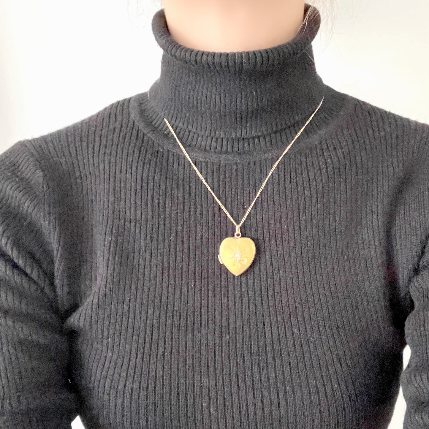 A gold-filled heart-shaped locket adorned with a small starburst motif. 小さなスターバーストモチーフがあしらわれた、ゴールドフィルドのハート型のロケット。