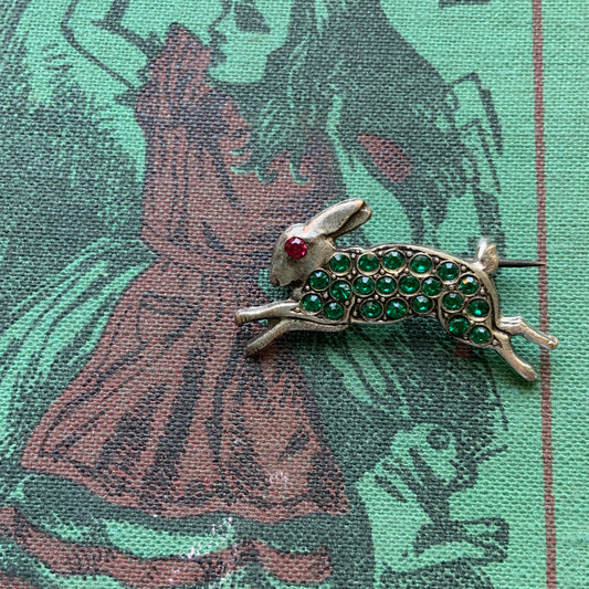 This silver brooch features a rabbit with green rhinestones adorning its body. グリーンのラインストーンをボディに纏ったうさぎのシルバーブローチ。