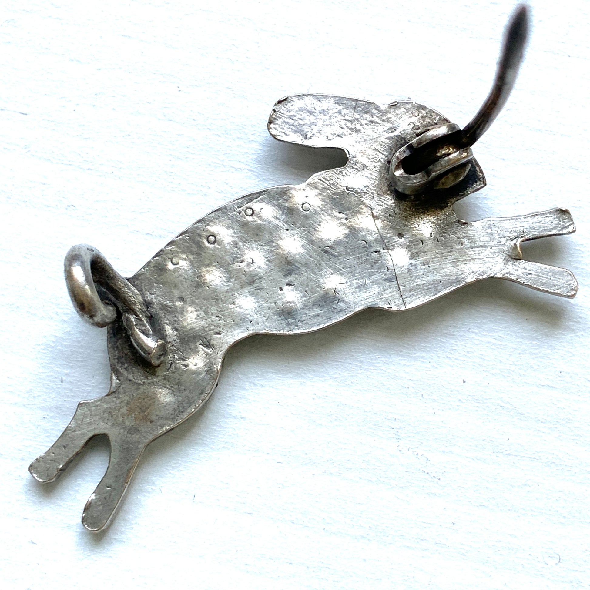 This silver brooch features a rabbit with green rhinestones adorning its body. グリーンのラインストーンをボディに纏ったうさぎのシルバーブローチ。