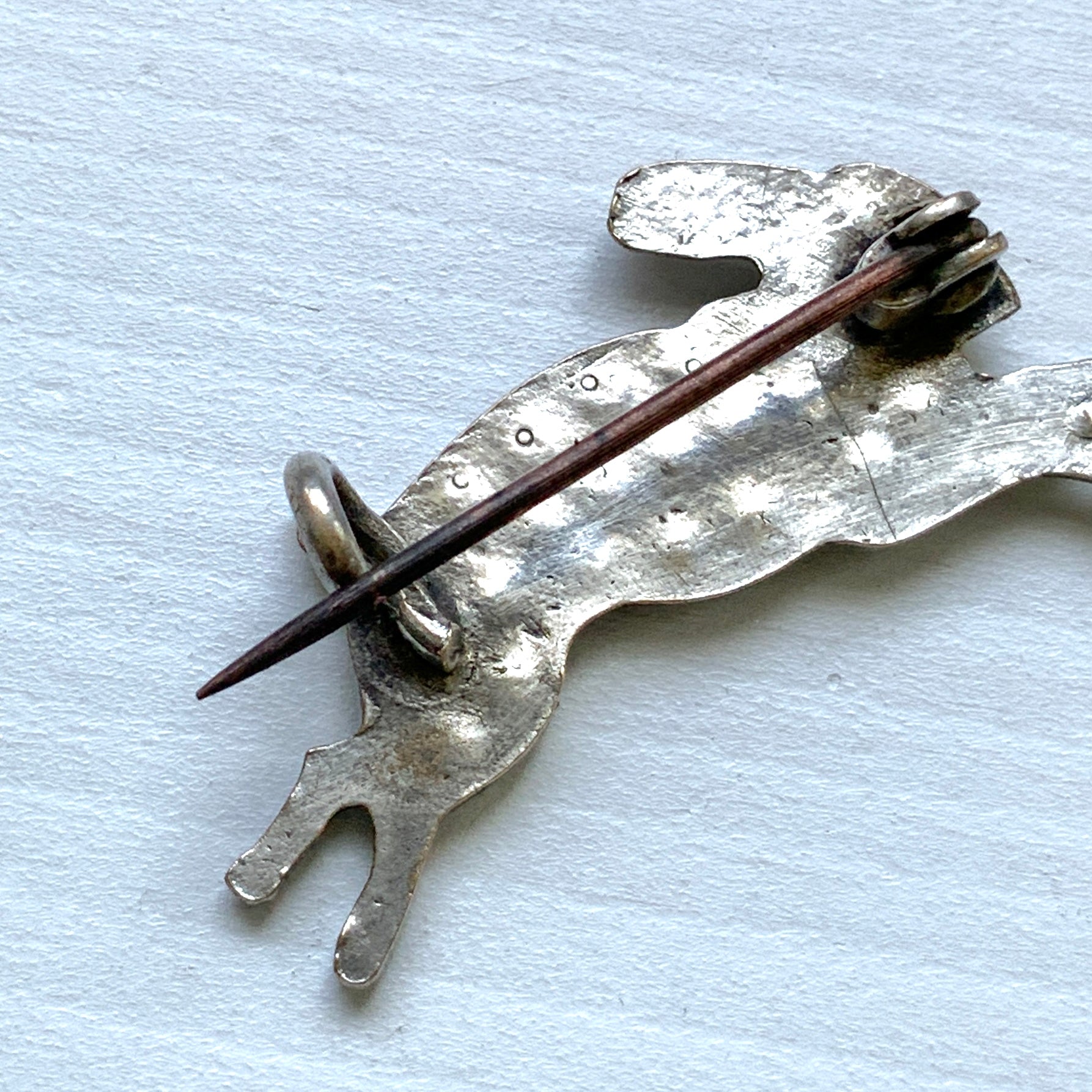 This silver brooch features a rabbit with green rhinestones adorning its body. グリーンのラインストーンをボディに纏ったうさぎのシルバーブローチ。