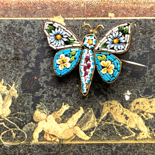 A micro mosaic butterfly brooch featuring delicate floral designs on its wings. お花が羽に入ったマイクロモザイク の蝶々のブローチ。