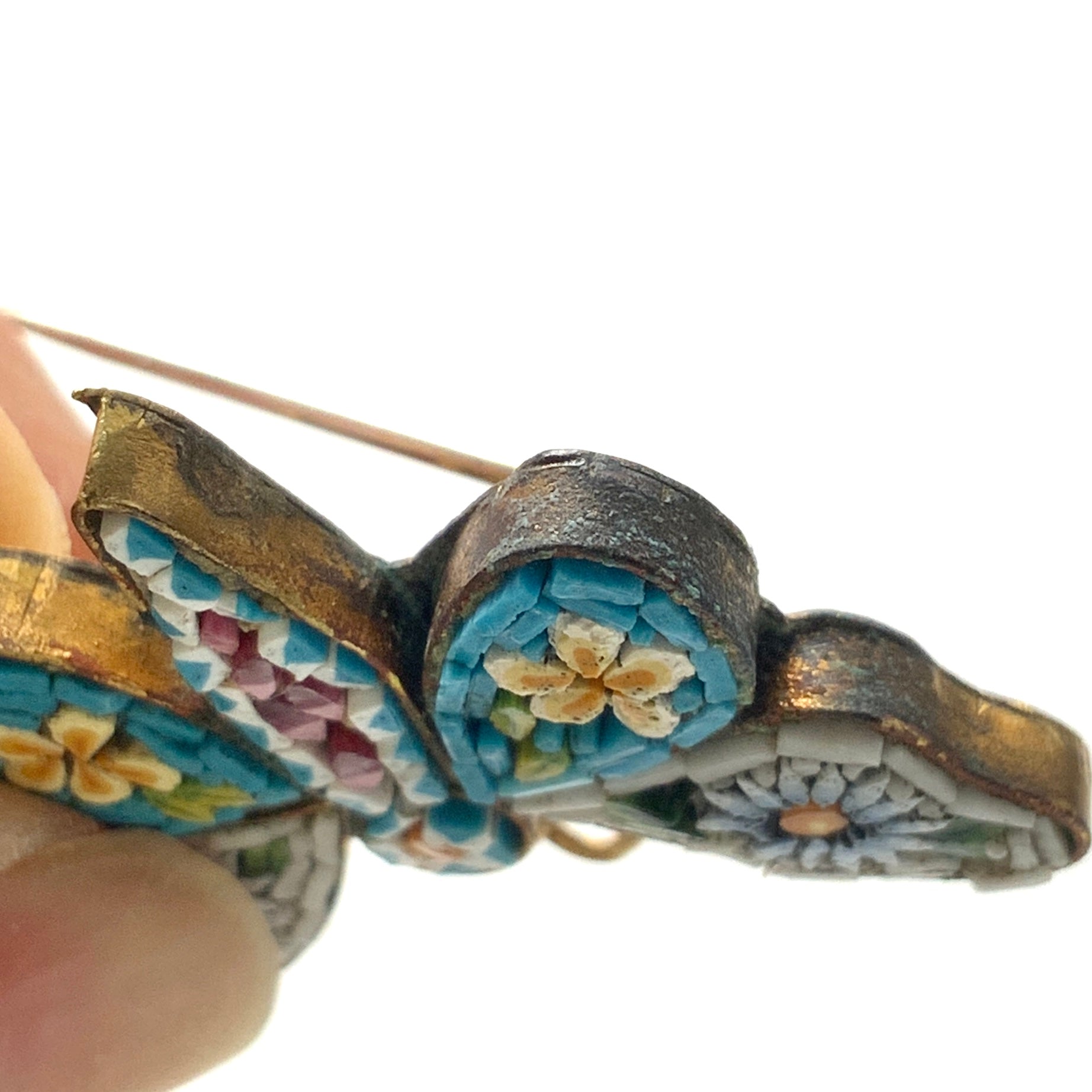 A micro mosaic butterfly brooch featuring delicate floral designs on its wings. お花が羽に入ったマイクロモザイク の蝶々のブローチ。