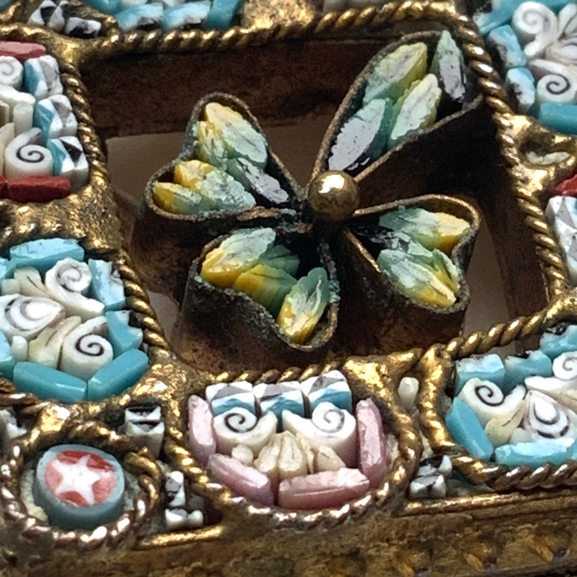 A brooch featuring a three-leaf clover set inside a diamond-shaped frame adorned with delicate detailing. 細かな飾りが飾られたダイヤ型のフレームの中に、三つ葉のクローバーが入ったブローチ。