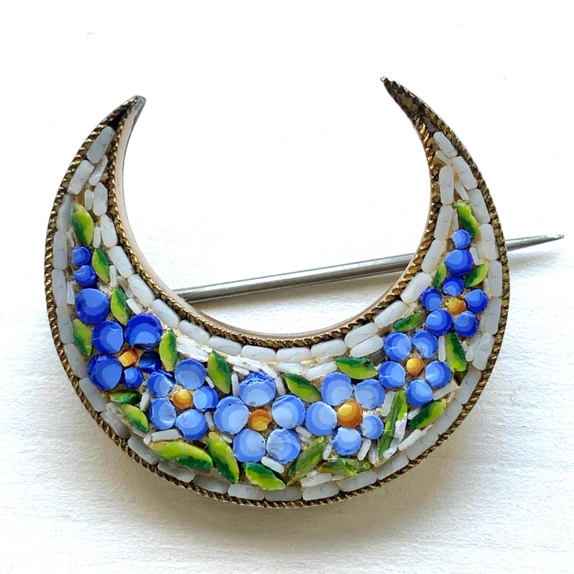 A crescent-shaped brooch adorned with charming blue micro-mosaic flowers resembling forget-me-nots. 勿忘草のような、かわいらしいブルーのお花のマイクロモザイク があしらわれた三日月型のブローチ。