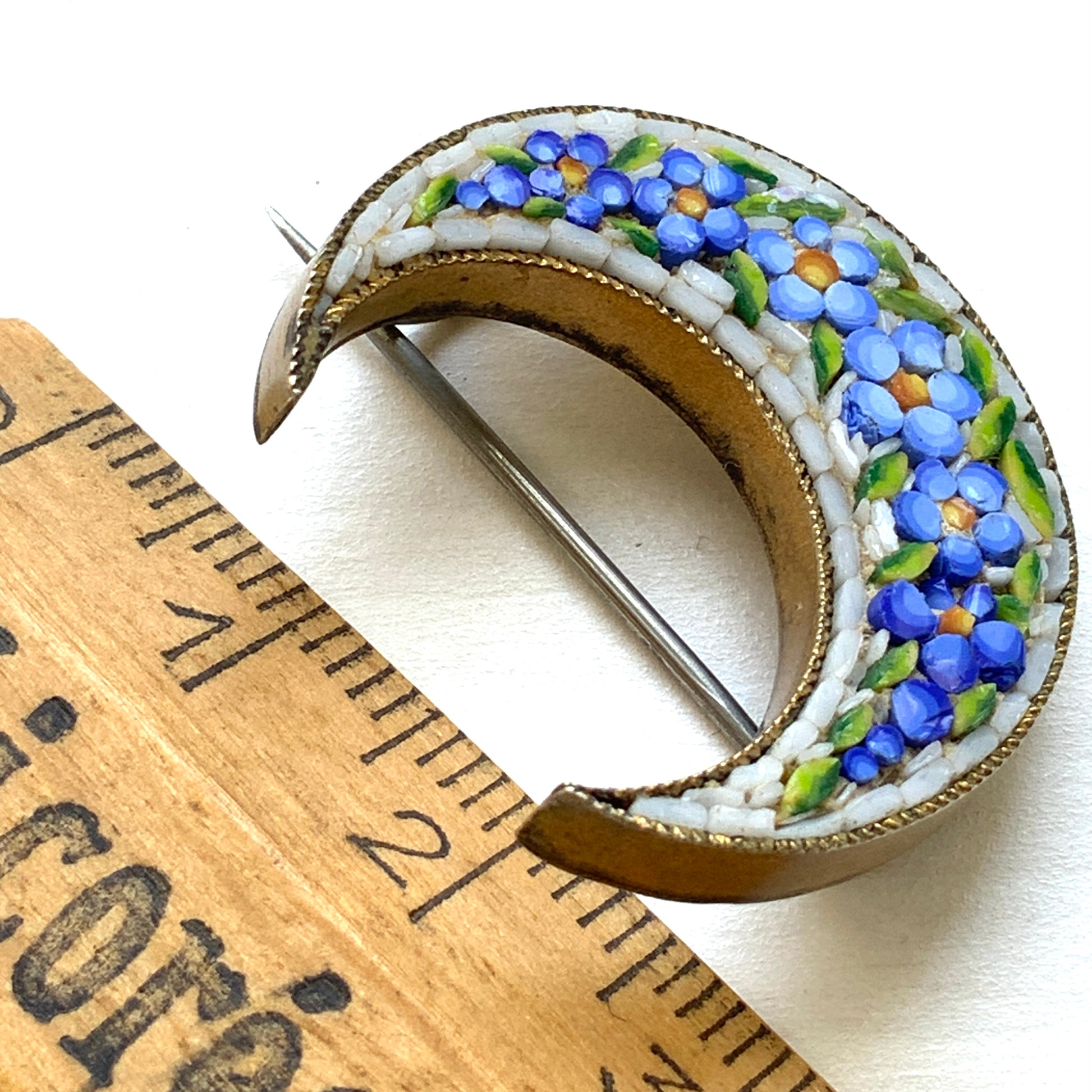 A crescent-shaped brooch adorned with charming blue micro-mosaic flowers resembling forget-me-nots. 勿忘草のような、かわいらしいブルーのお花のマイクロモザイク があしらわれた三日月型のブローチ。
