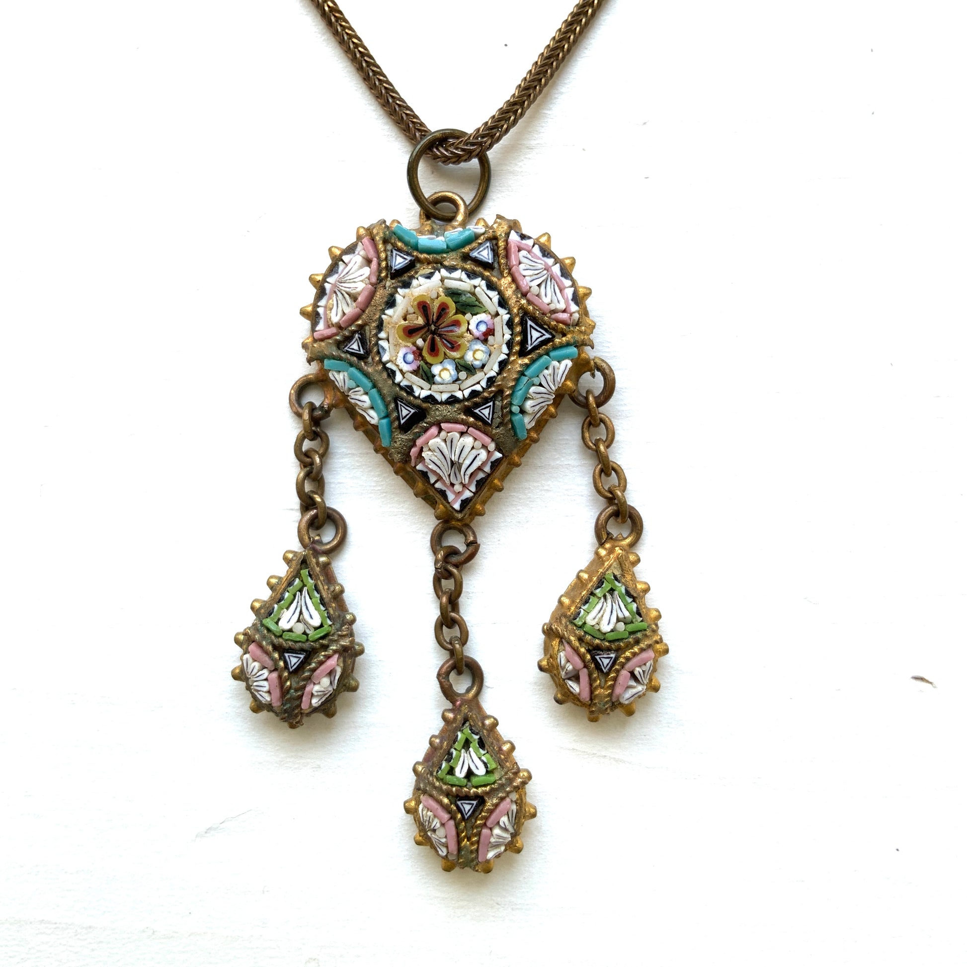 A heart-shaped micro mosaic pendant suspends three delicate teardrop-shaped micro mosaics, forming a beautifully balanced necklace. ハート型のマイクロモザイク から三つのマイクロモザイク ティアドロップが下がったネックレス。