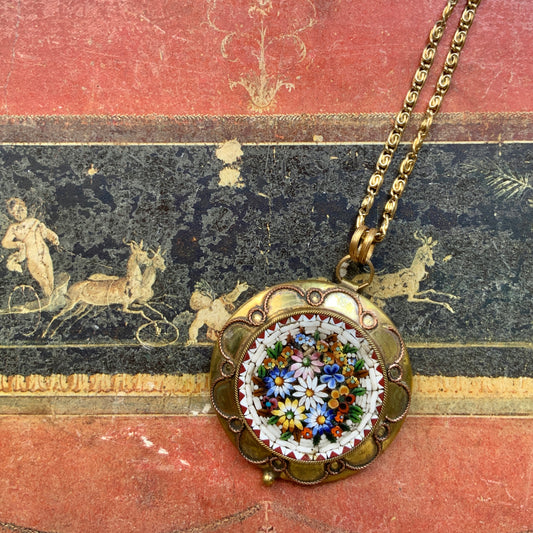 This pendant necklace features a base of gold-tone metal adorned with colorful floral micro-mosaics.  ゴールドトーンメタルをベースに、カラフルな花々のマイクロモザイクがあしらわれたペンダントネックレス。