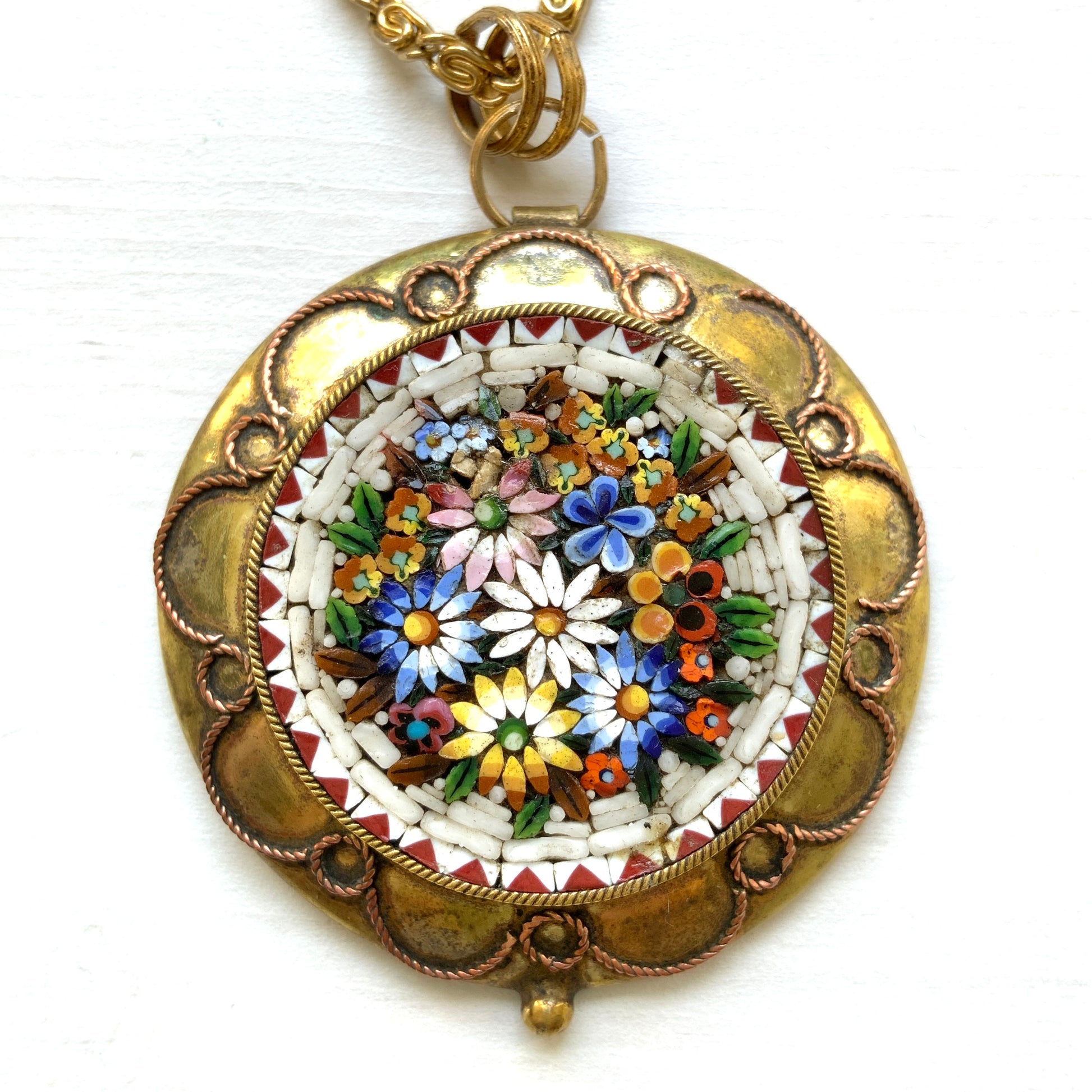 This pendant necklace features a base of gold-tone metal adorned with colorful floral micro-mosaics.  ゴールドトーンメタルをベースに、カラフルな花々のマイクロモザイクがあしらわれたペンダントネックレス。