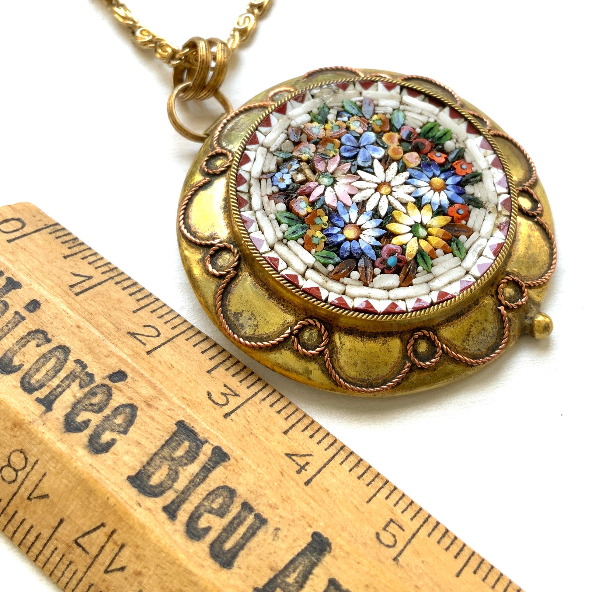 This pendant necklace features a base of gold-tone metal adorned with colorful floral micro-mosaics.  ゴールドトーンメタルをベースに、カラフルな花々のマイクロモザイクがあしらわれたペンダントネックレス。
