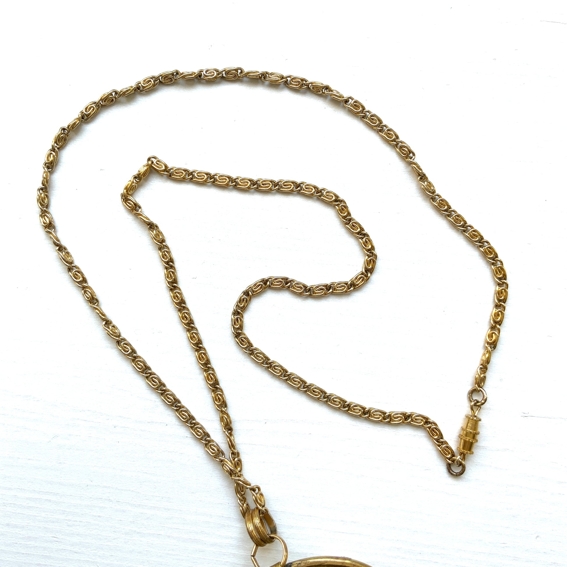 This pendant necklace features a base of gold-tone metal adorned with colorful floral micro-mosaics.  ゴールドトーンメタルをベースに、カラフルな花々のマイクロモザイクがあしらわれたペンダントネックレス。