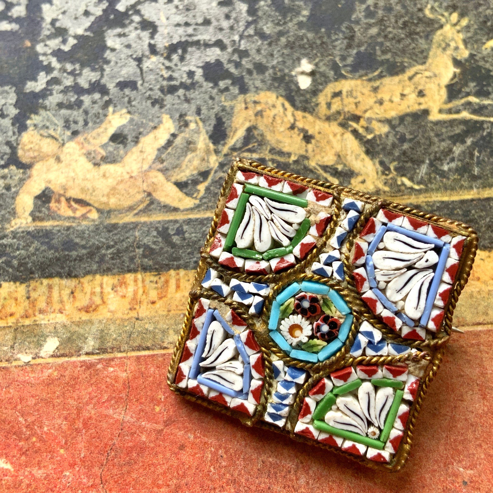 A square-shaped brooch adorned with colorful micro-mosaics. カラフルなマイクロモザイク が施されたスクエア型ブローチ。