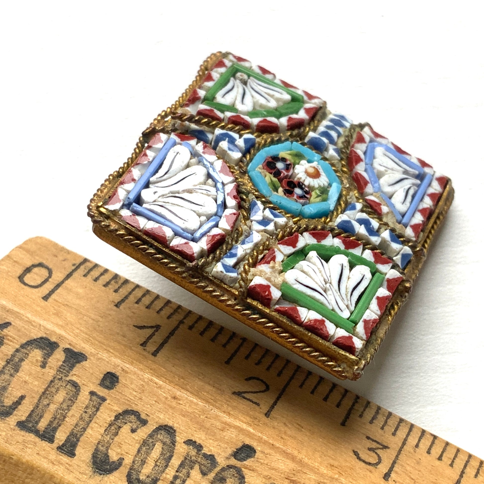 A square-shaped brooch adorned with colorful micro-mosaics. カラフルなマイクロモザイク が施されたスクエア型ブローチ。