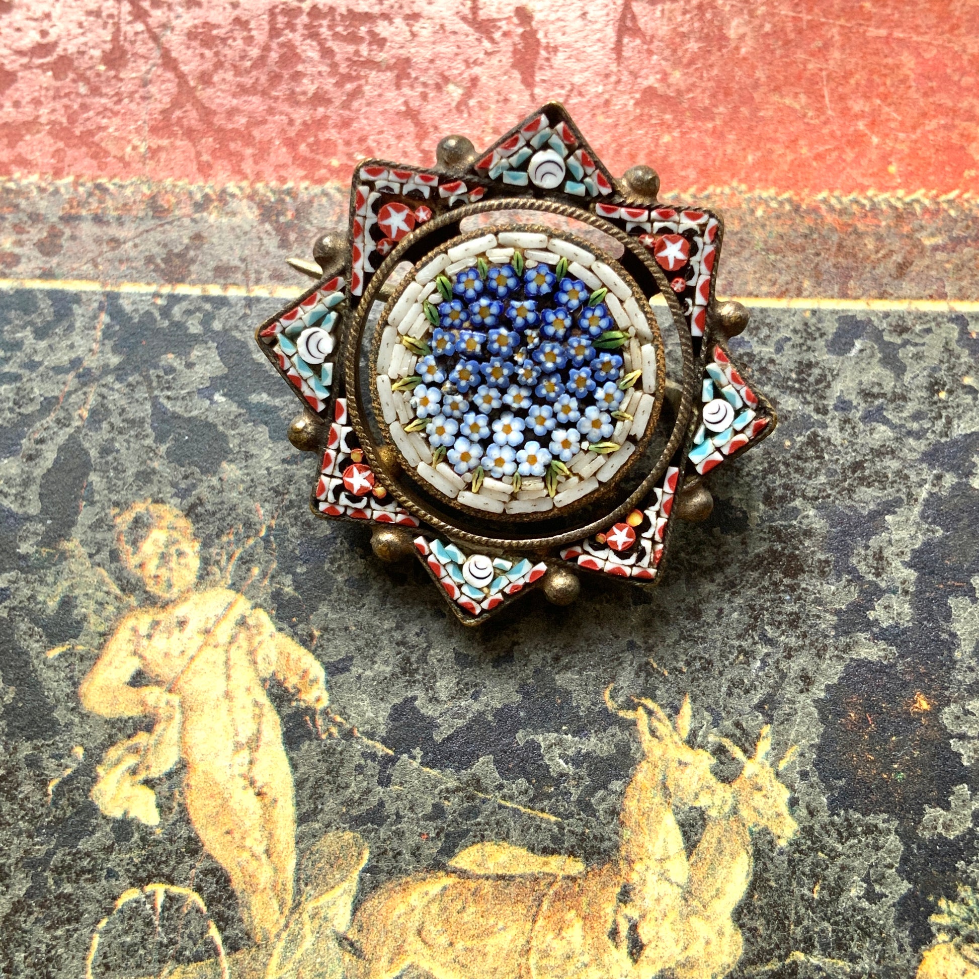 A star-shaped micro mosaic brooch filled with tiny, charming blue flowers reminiscent of forget-me-nots. 勿忘草のような、かわいらしい青い小花がぎっしりと詰め込まれた星型のマイクロモザイクブローチ。