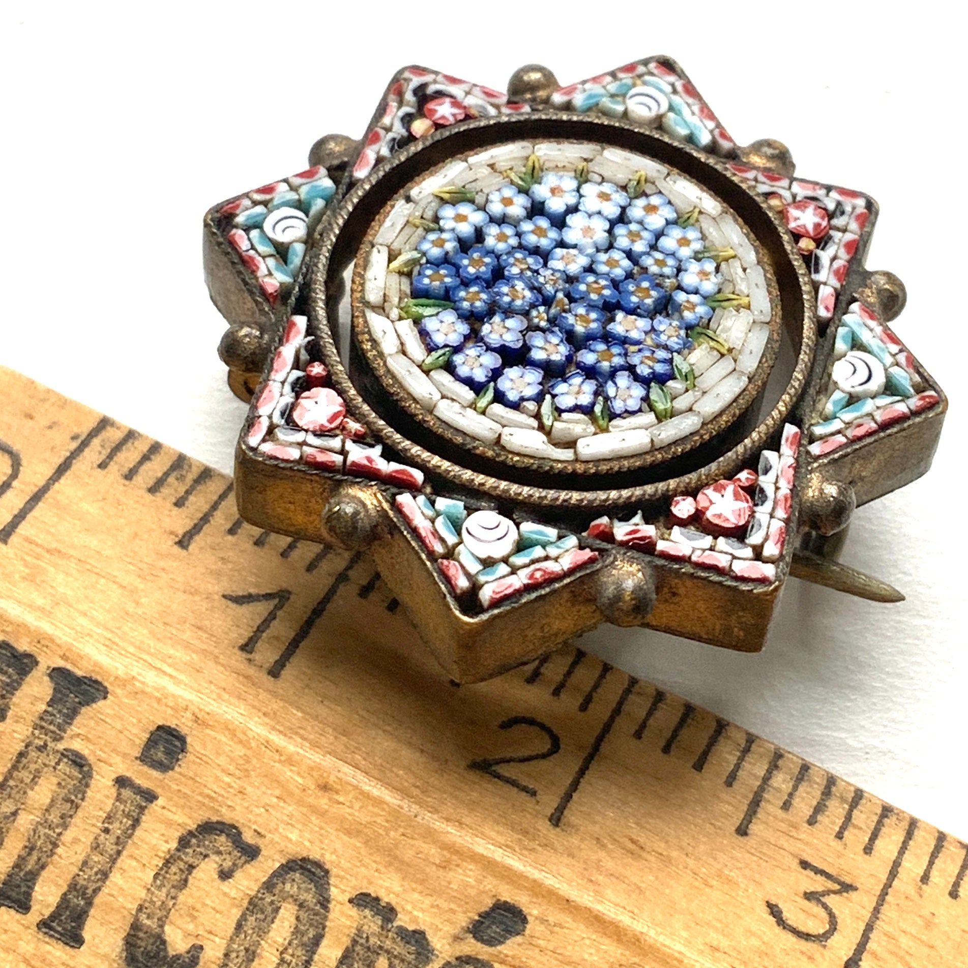 A star-shaped micro mosaic brooch filled with tiny, charming blue flowers reminiscent of forget-me-nots. 勿忘草のような、かわいらしい青い小花がぎっしりと詰め込まれた星型のマイクロモザイクブローチ。