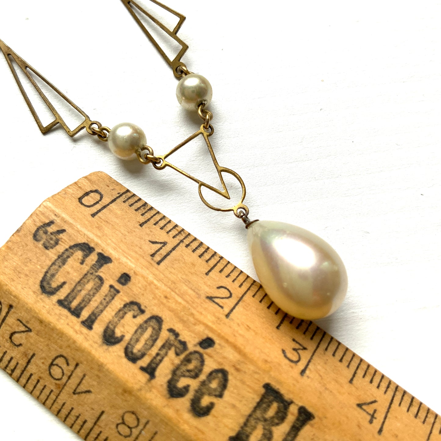 A necklace combining gold-tone metal links and glass pearls. ゴールドトーンメタルのリンクとグラスパールを組み合わせたネックレス。