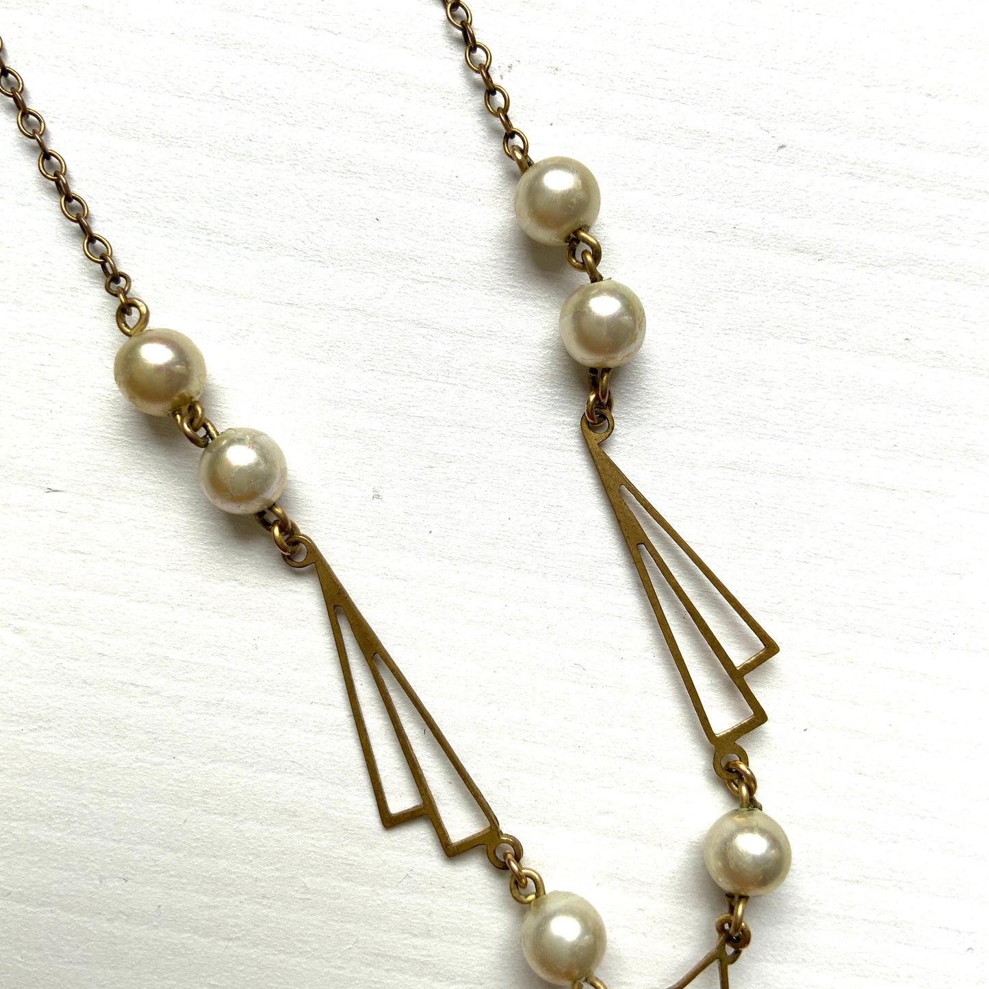 A necklace combining gold-tone metal links and glass pearls. ゴールドトーンメタルのリンクとグラスパールを組み合わせたネックレス。