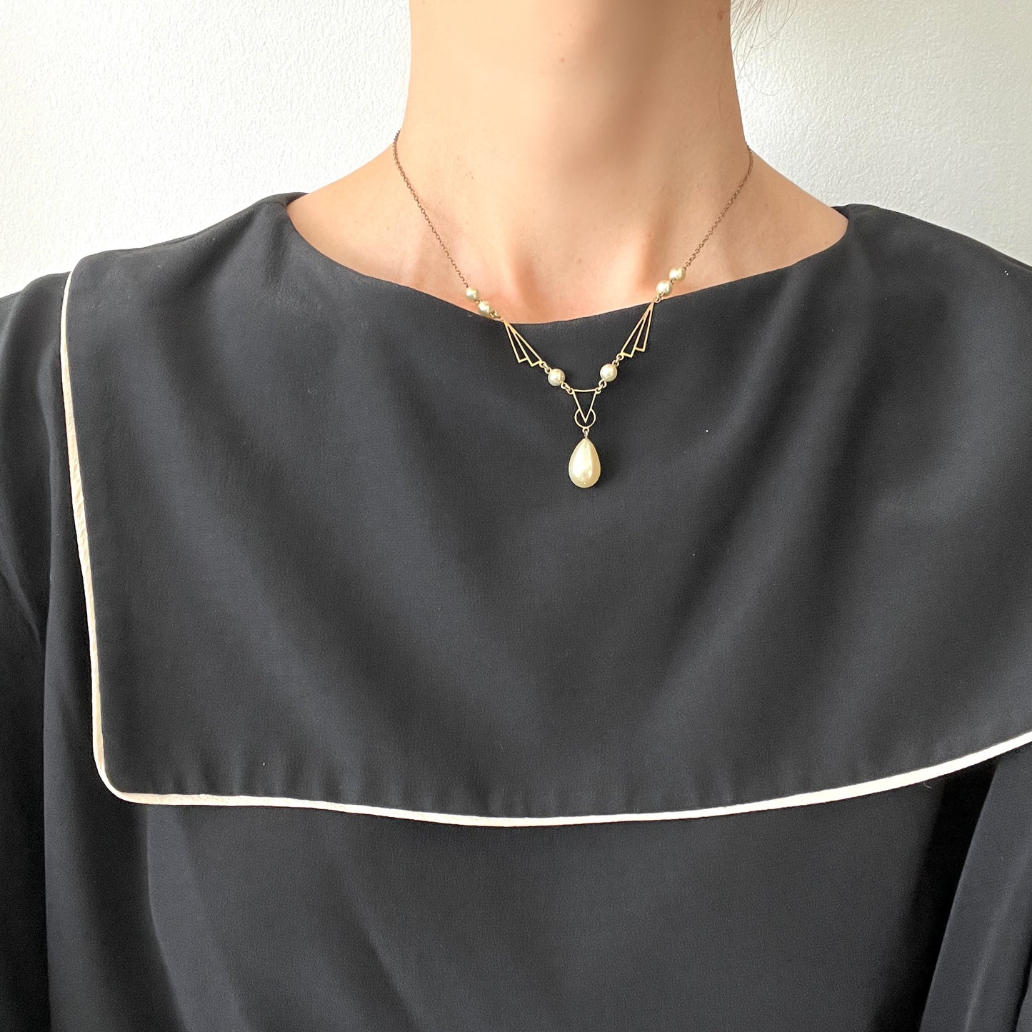 A necklace combining gold-tone metal links and glass pearls. ゴールドトーンメタルのリンクとグラスパールを組み合わせたネックレス。
