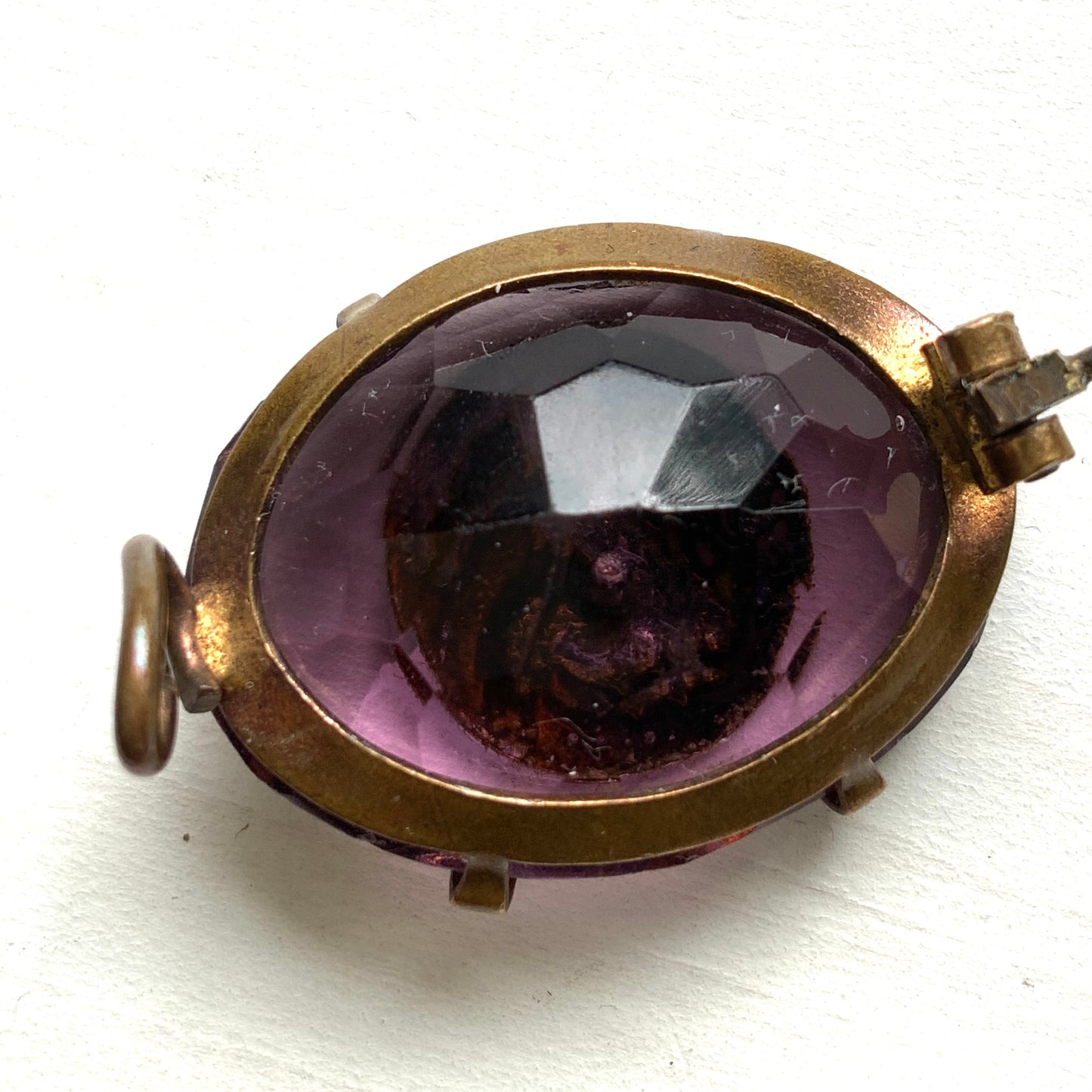 An antique brooch featuring a medal of the Virgin Mary set at the centre of a deep purple faceted glass stone. 深いパープルのカットガラスの中央に、聖母マリアを象ったメダルをセットしたアンティークブローチ。