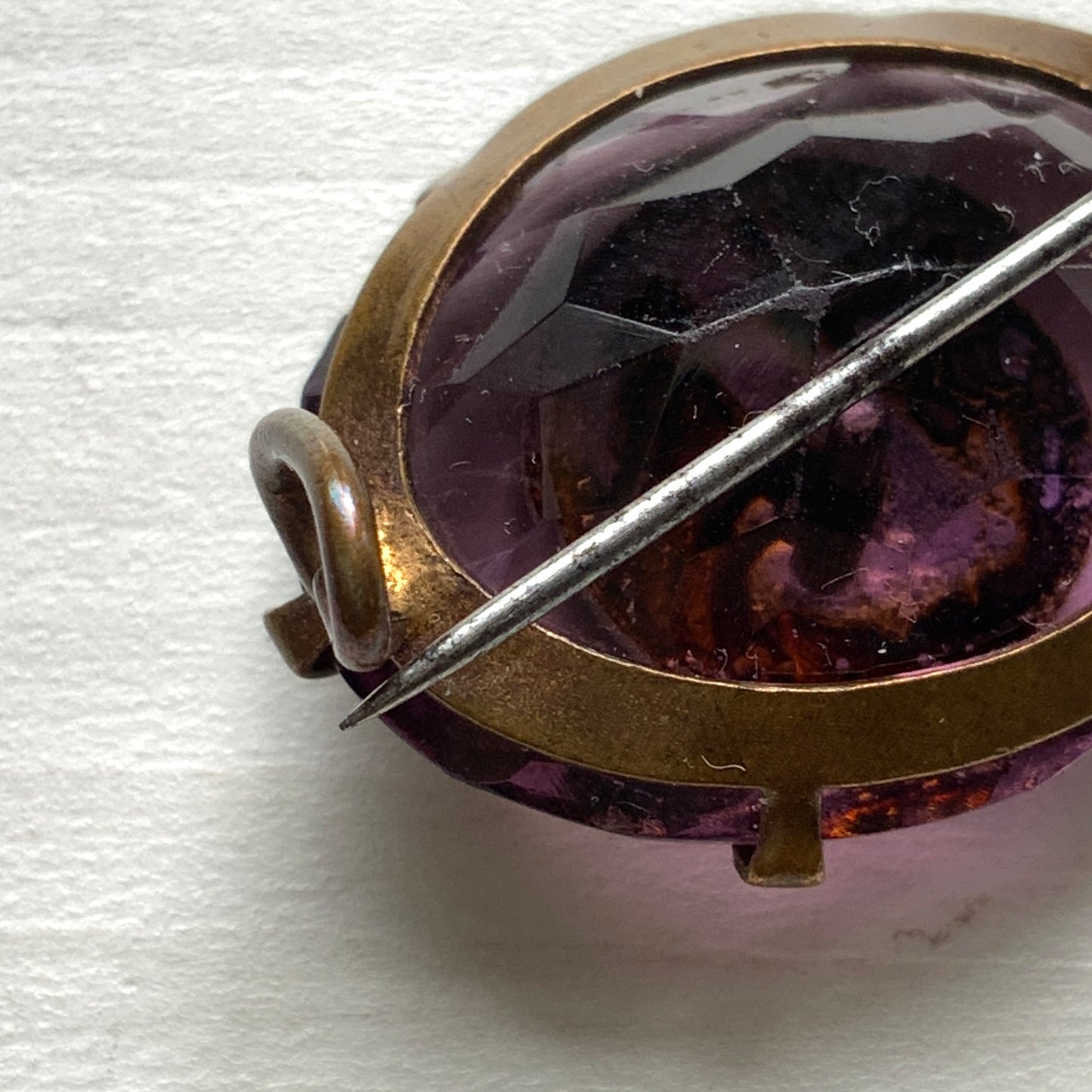 An antique brooch featuring a medal of the Virgin Mary set at the centre of a deep purple faceted glass stone. 深いパープルのカットガラスの中央に、聖母マリアを象ったメダルをセットしたアンティークブローチ。