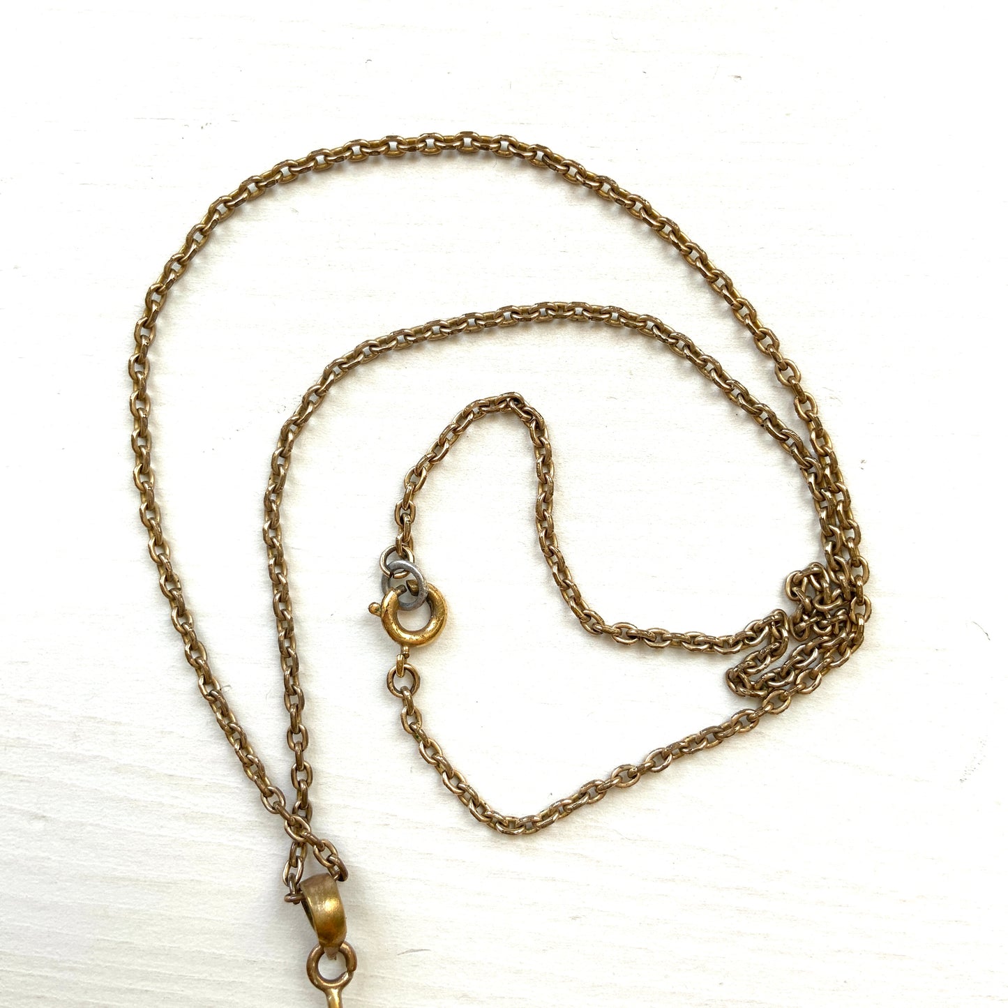 An antique pendant necklace featuring a starburst design with a mysterious glass stone known as Saphiret set in the centre. 神秘的な輝きを放つサフィレットを中央に添えた、ラインストーンのスターバーストデザインのペンダントネックレス。