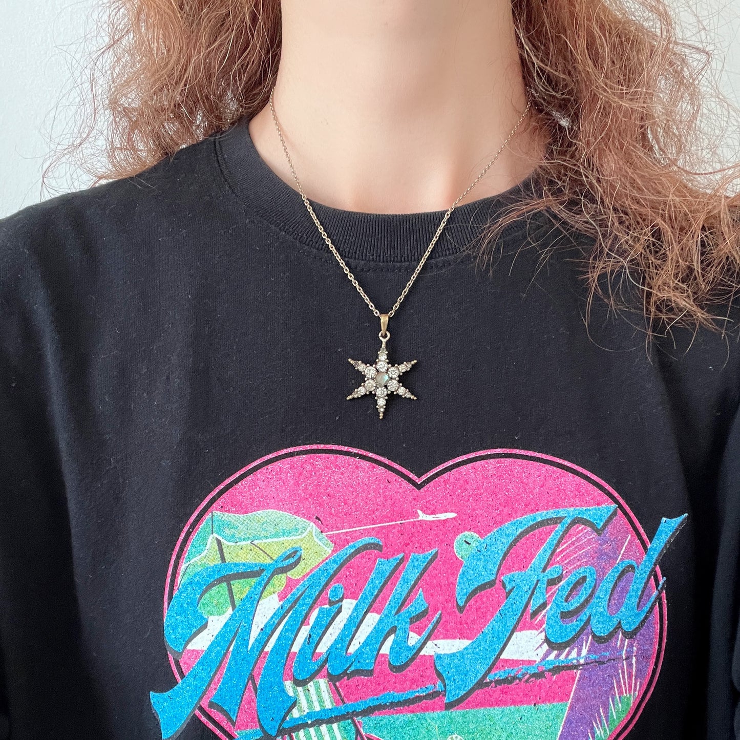 An antique pendant necklace featuring a starburst design with a mysterious glass stone known as Saphiret set in the centre. 神秘的な輝きを放つサフィレットを中央に添えた、ラインストーンのスターバーストデザインのペンダントネックレス。
