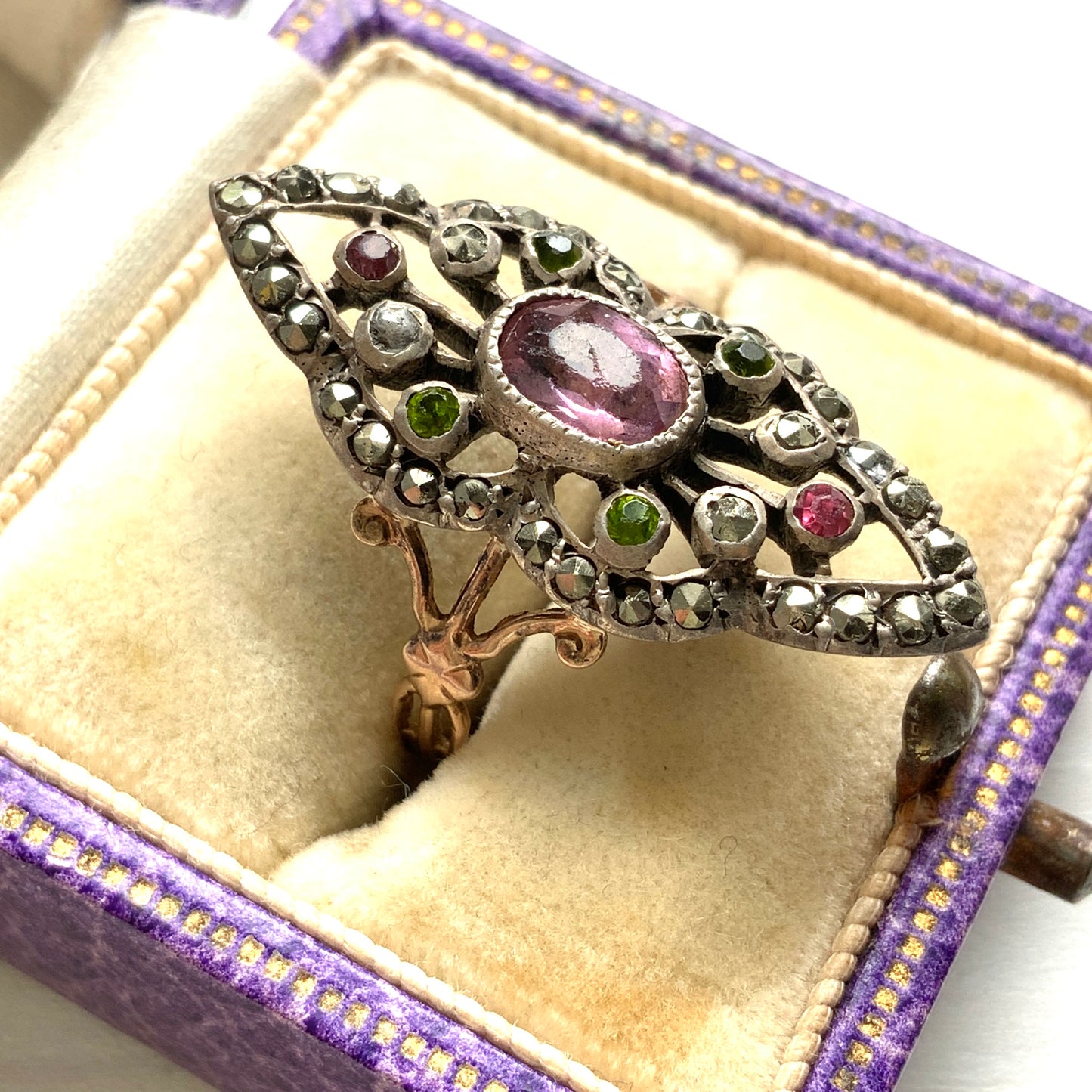 A diamond-shaped ring adorned with amethyst glass, peridot glass, and marcasite. ダイヤモンドシェイプに、アメジストグラス、ペリドットグラス、マーカサイトがあしらわれたリング。
