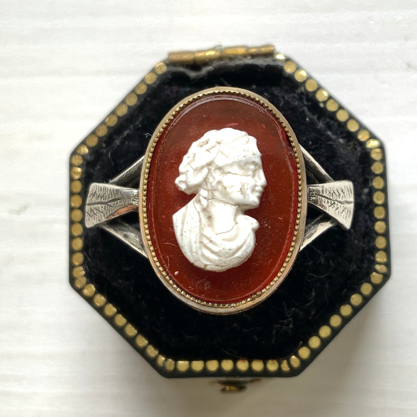 A Victorian ring with a cameo composed of a red glass base and a white porcelain overlay, imitating the look of carnelian two-layer stone. カーネリアンの二層石のカメオを、赤いガラスのベースと白い陶器のカメオで再現したヴィクトリア時代のリング。