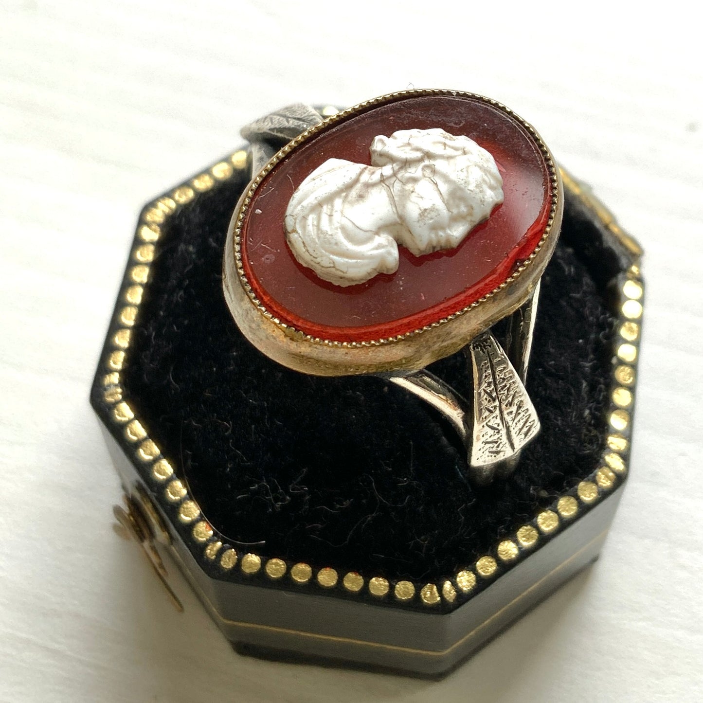 A Victorian ring with a cameo composed of a red glass base and a white porcelain overlay, imitating the look of carnelian two-layer stone. カーネリアンの二層石のカメオを、赤いガラスのベースと白い陶器のカメオで再現したヴィクトリア時代のリング。