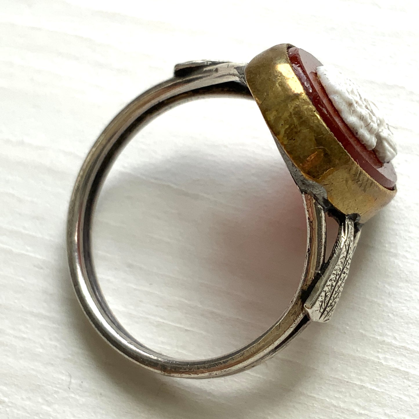 A Victorian ring with a cameo composed of a red glass base and a white porcelain overlay, imitating the look of carnelian two-layer stone. カーネリアンの二層石のカメオを、赤いガラスのベースと白い陶器のカメオで再現したヴィクトリア時代のリング。