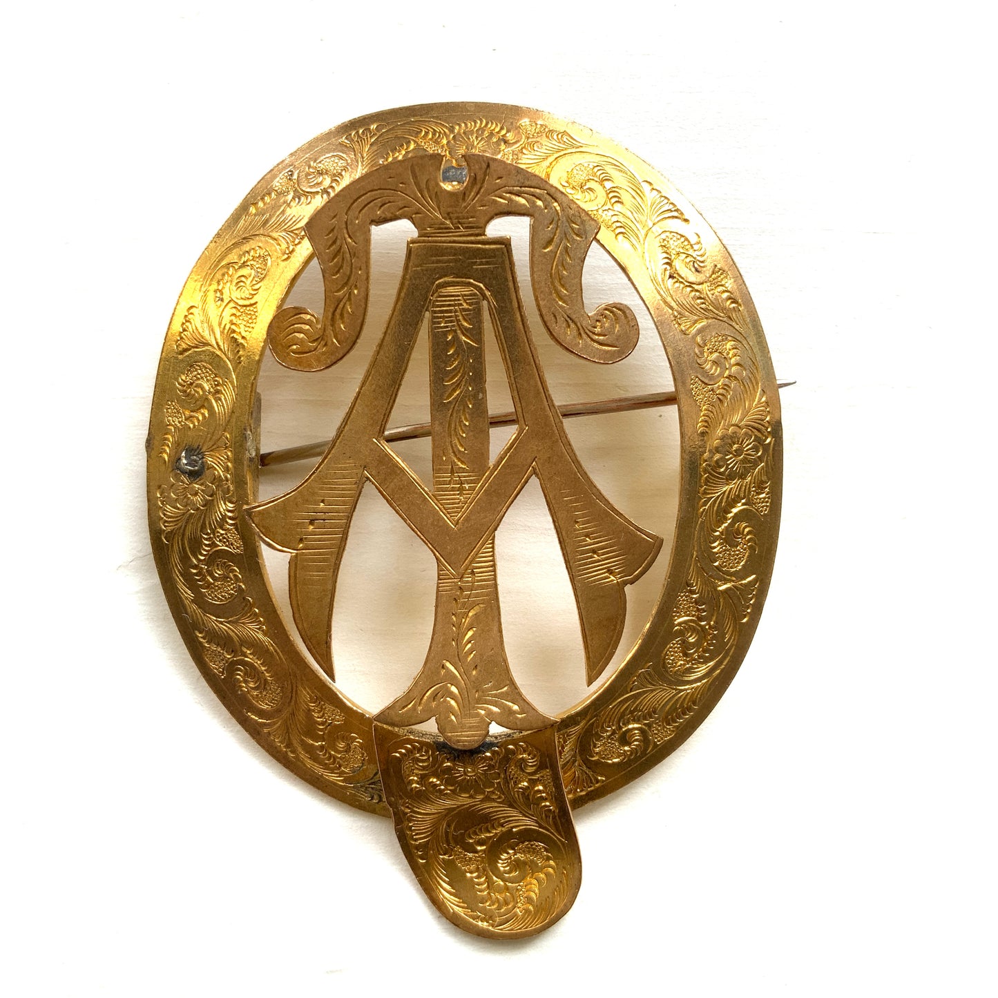 A gold-tone monogram brooch beautifully engraved with a delicate botanical motif. 美しい植物モチーフが彫られたゴールドトーンのモノグラムブローチ。