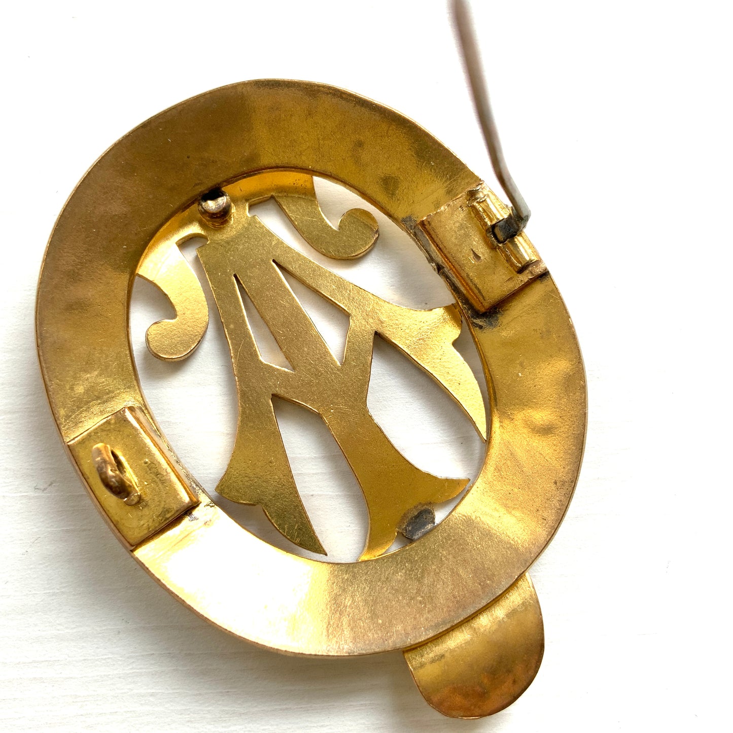 A gold-tone monogram brooch beautifully engraved with a delicate botanical motif. 美しい植物モチーフが彫られたゴールドトーンのモノグラムブローチ。