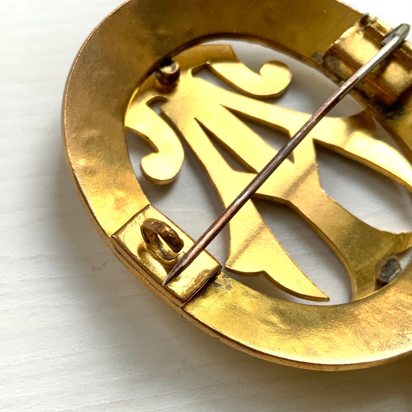 A gold-tone monogram brooch beautifully engraved with a delicate botanical motif. 美しい植物モチーフが彫られたゴールドトーンのモノグラムブローチ。