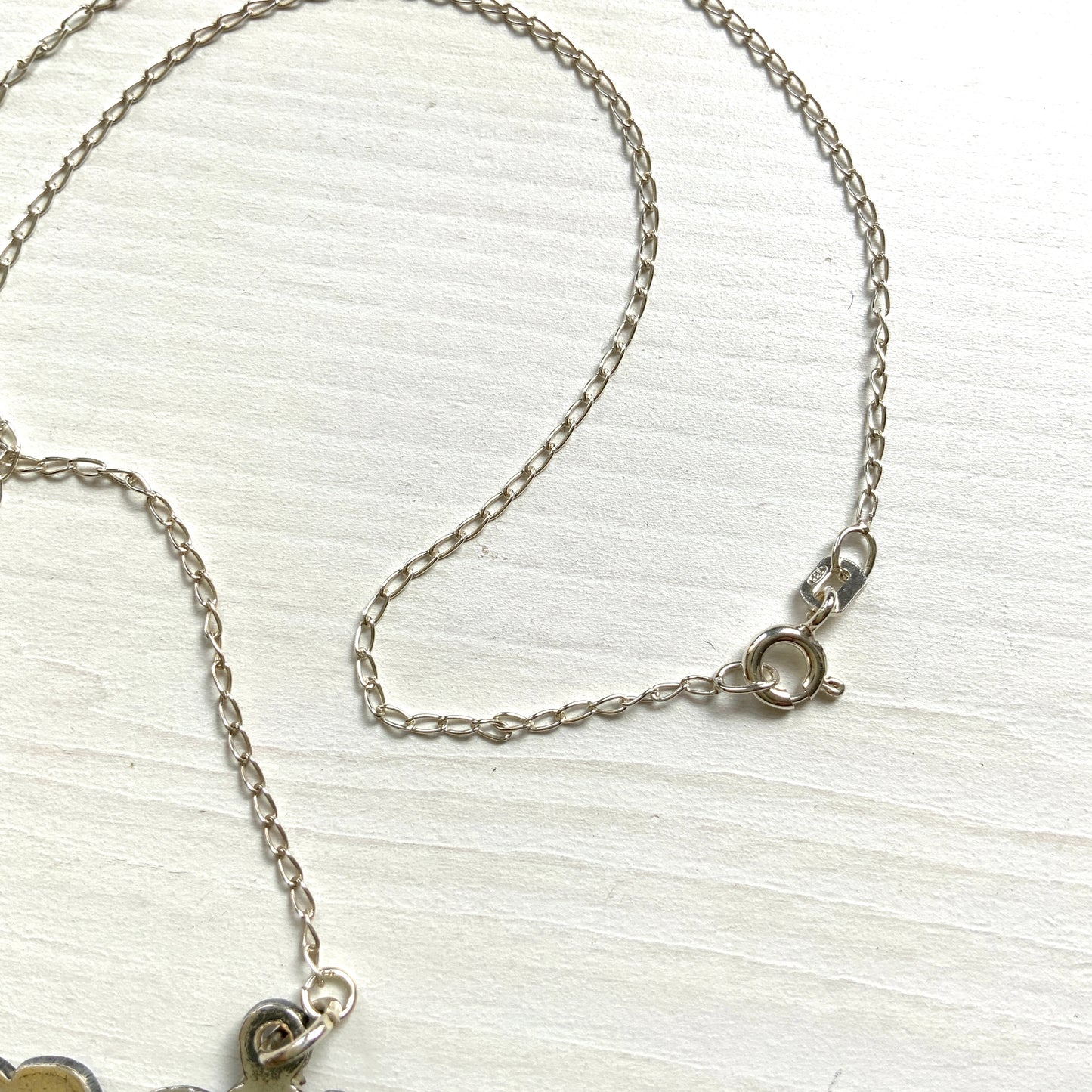 A necklace featuring the letter “W”, beautifully engraved with a botanical motif. 美しい植物モチーフのエングレービングが施された“W”のネックレス。