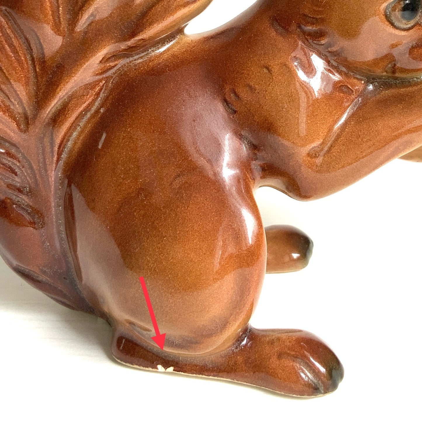 A charming ceramic squirrel figurine holding a nut. ナッツを抱えた、愛らしいセラミック製のリスのフィギュリン。