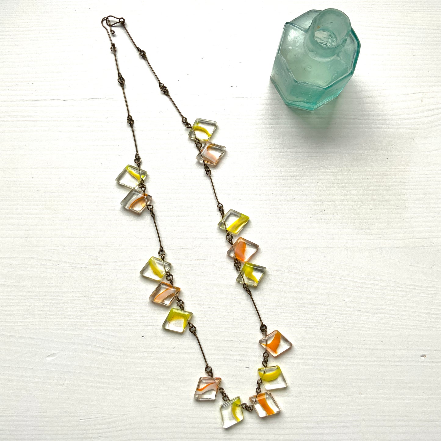 Necklace featuring diamond-shaped clear glass beads infused with shades of yellow, orange, and white. クリアのダイヤ型グラスにイエロー、オレンジ、ホワイトのカラーが入ったビーズを使ったネックレス。