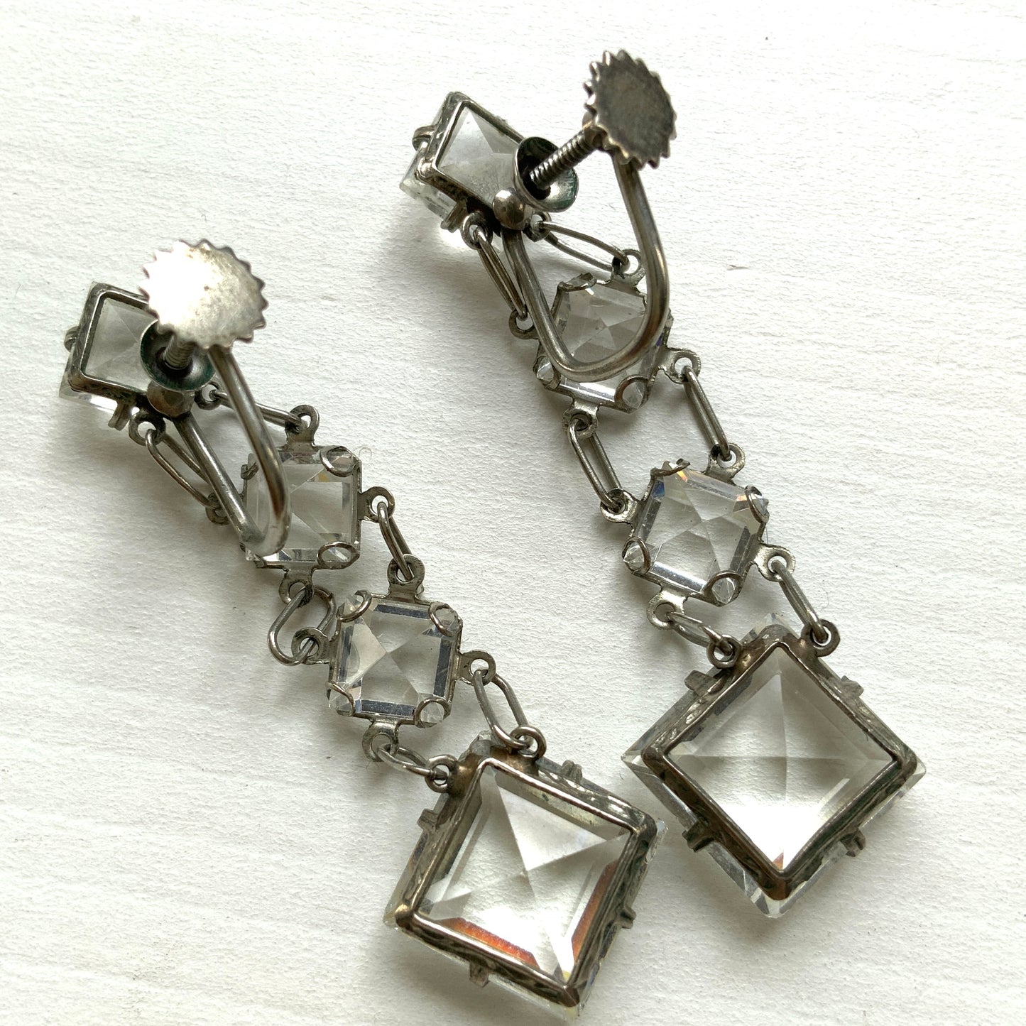 Screw-back earrings featuring clear diamond-shaped glass drops.クリアのダイヤ型グラスが揺れる、スクリューイヤリング。