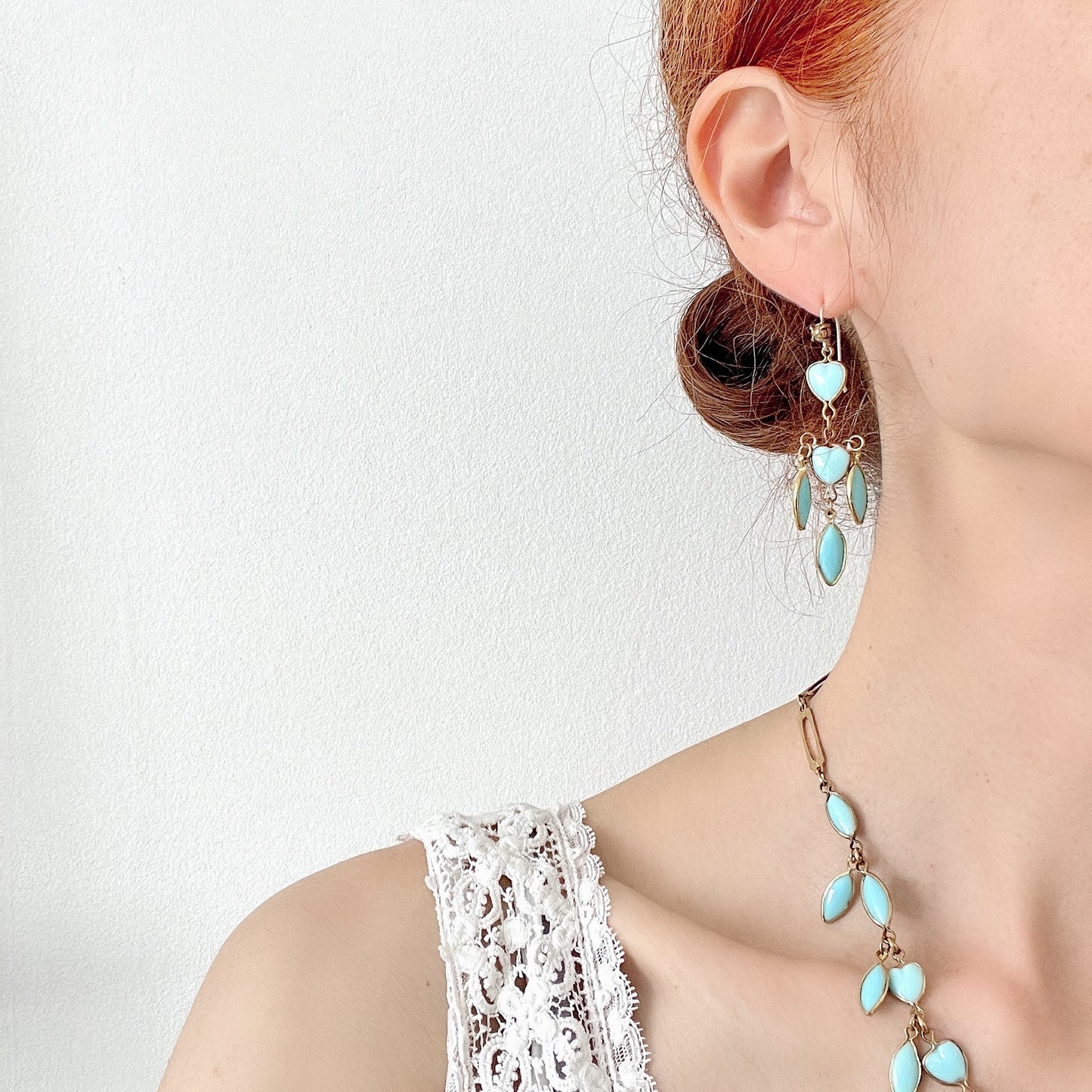 A pair of earrings featuring a pale turquoise heart glass chain adorned with marquise-shaped glass fringe. 淡いターコイズカラーのハートグラスチェーンに、マーキス 型のグラスのフリンジがついたピアス。