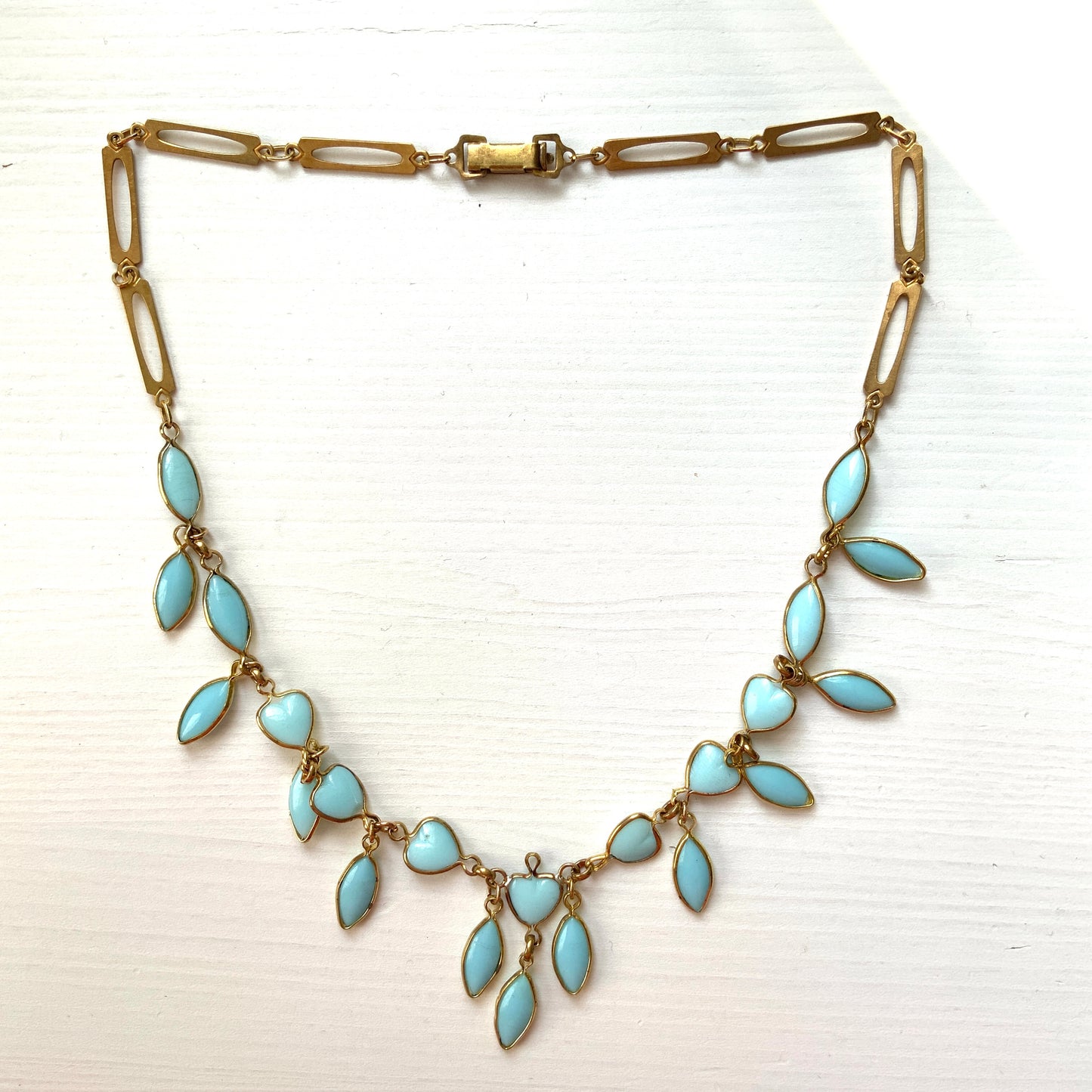 This necklace features a delicate chain of pale turquoise heart-shaped glass links, accented with marquise-shaped glass fringe. 淡いターコイズカラーのハートグラスチェーンに、マーキス 型のグラスのフリンジがついたネックレス。