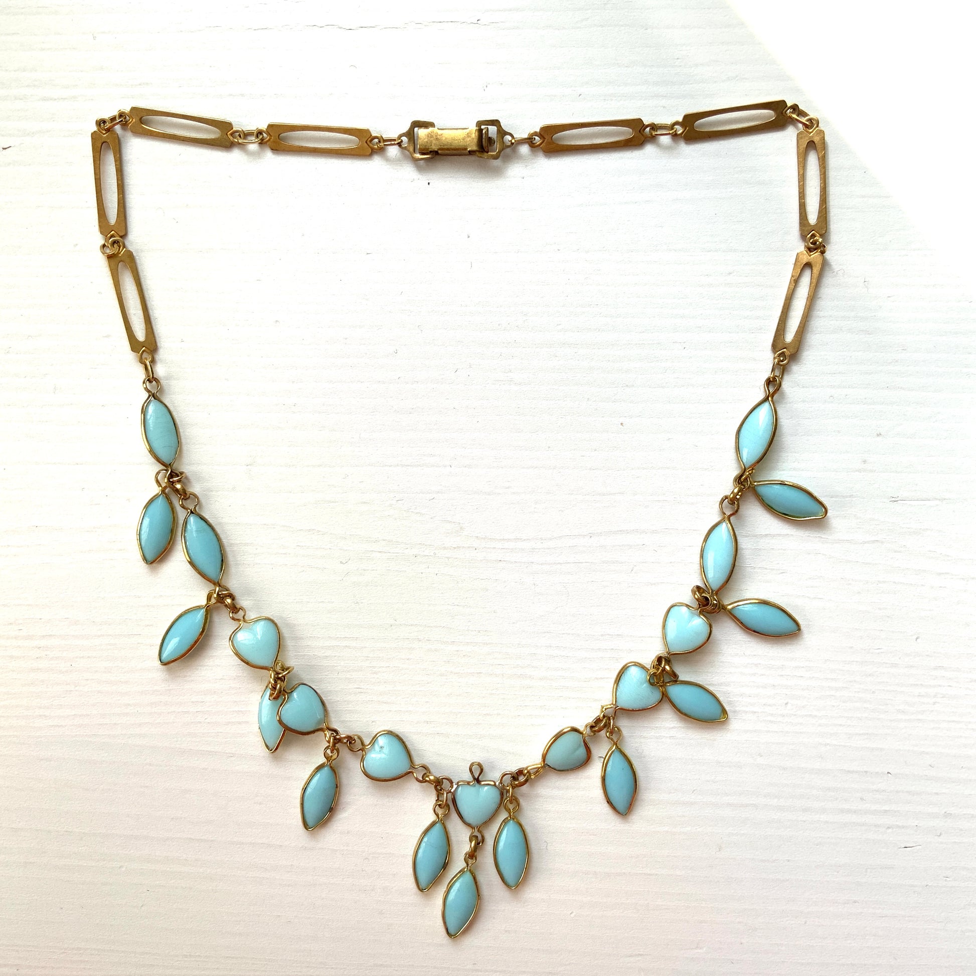 This necklace features a delicate chain of pale turquoise heart-shaped glass links, accented with marquise-shaped glass fringe. 淡いターコイズカラーのハートグラスチェーンに、マーキス 型のグラスのフリンジがついたネックレス。
