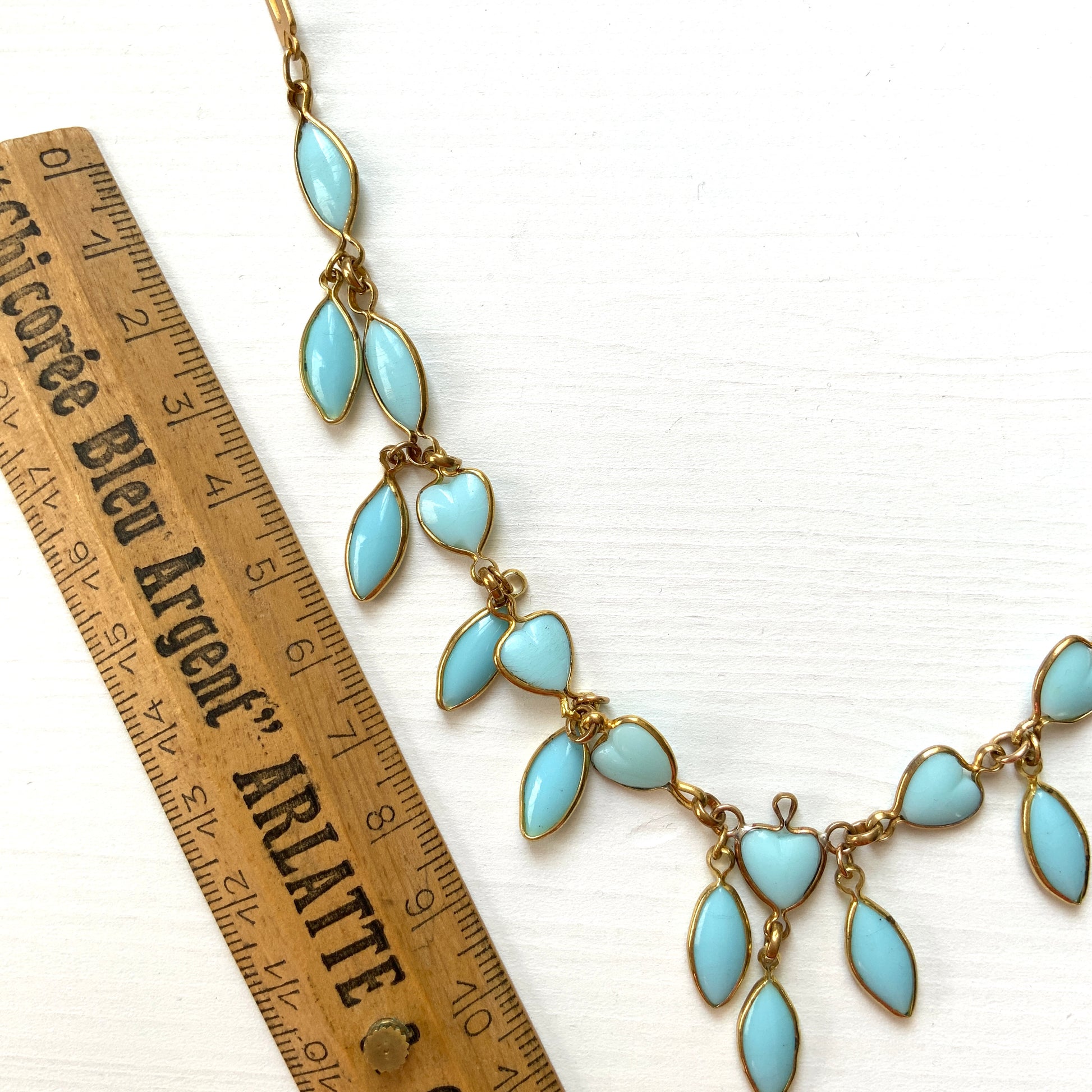 This necklace features a delicate chain of pale turquoise heart-shaped glass links, accented with marquise-shaped glass fringe. 淡いターコイズカラーのハートグラスチェーンに、マーキス 型のグラスのフリンジがついたネックレス。