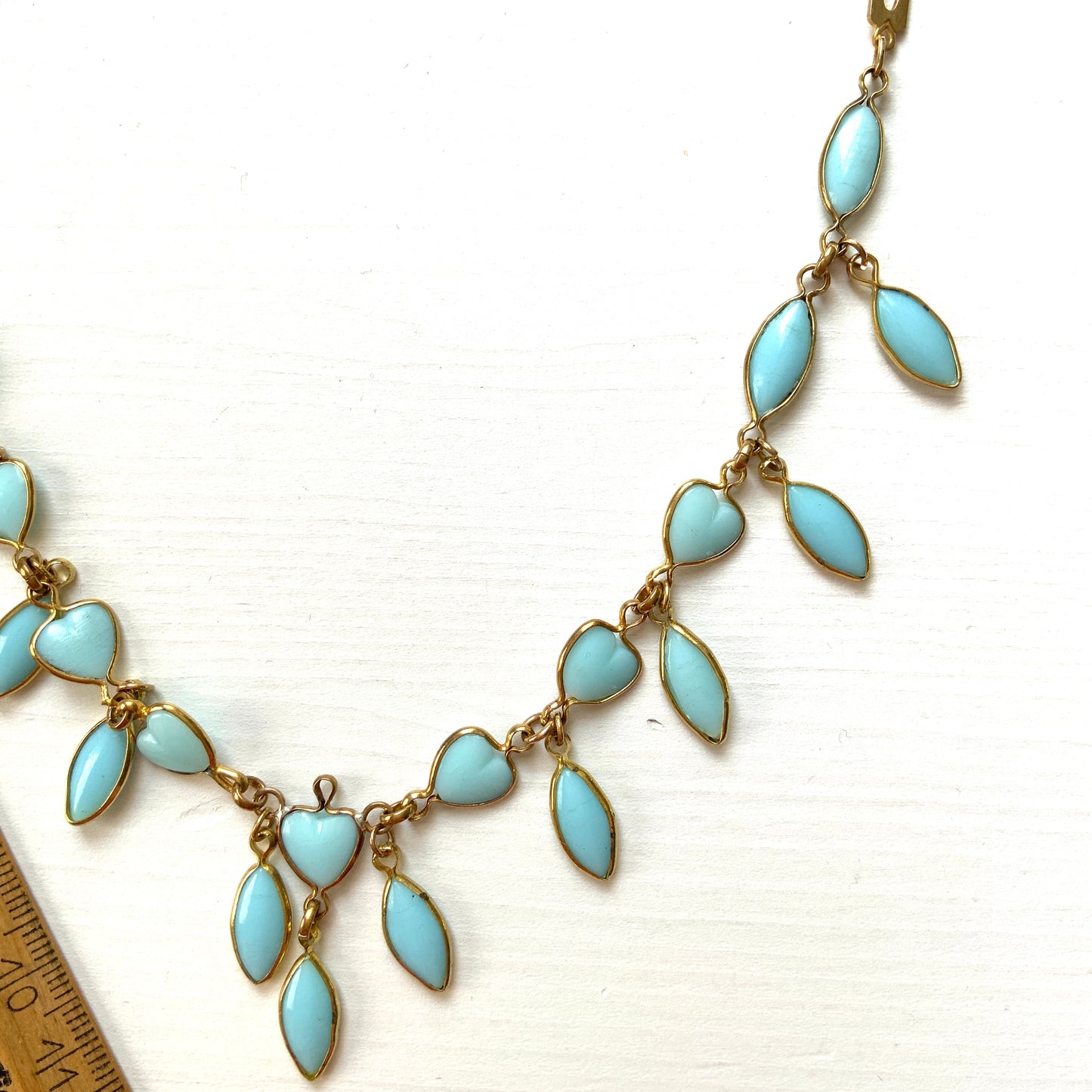 This necklace features a delicate chain of pale turquoise heart-shaped glass links, accented with marquise-shaped glass fringe. 淡いターコイズカラーのハートグラスチェーンに、マーキス 型のグラスのフリンジがついたネックレス。