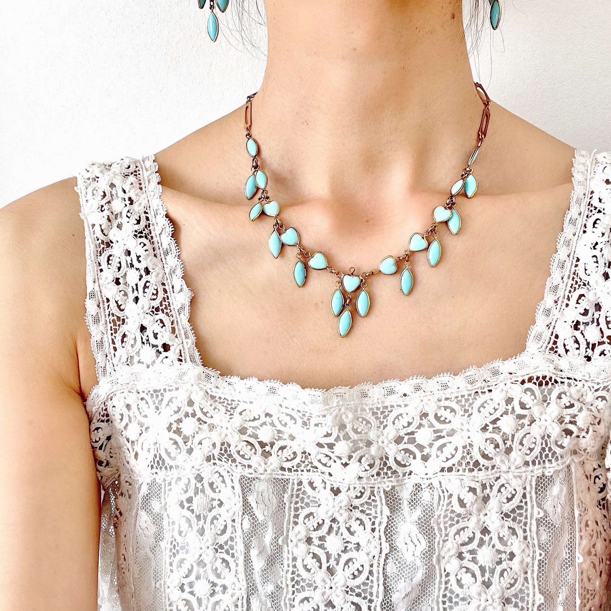 This necklace features a delicate chain of pale turquoise heart-shaped glass links, accented with marquise-shaped glass fringe. 淡いターコイズカラーのハートグラスチェーンに、マーキス 型のグラスのフリンジがついたネックレス。