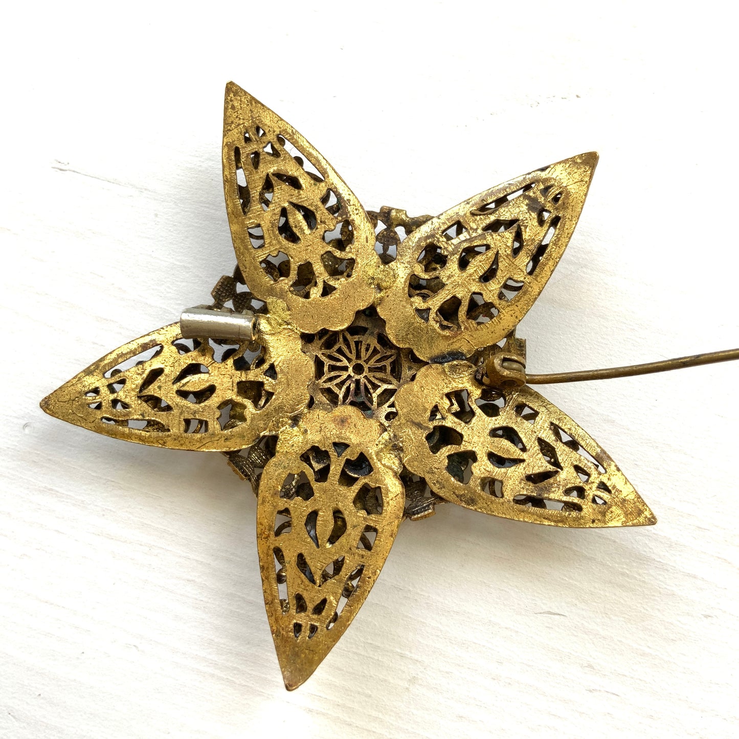 A beautiful vintage brooch featuring a star-shaped design crafted in intricate gold-tone filigree, adorned with multicoloured rhinestones. ゴールドトーンの繊細なフィリグリー細工でかたどられた星に、色とりどりのラインストーンがあしらわれたヴィンテージブローチ。