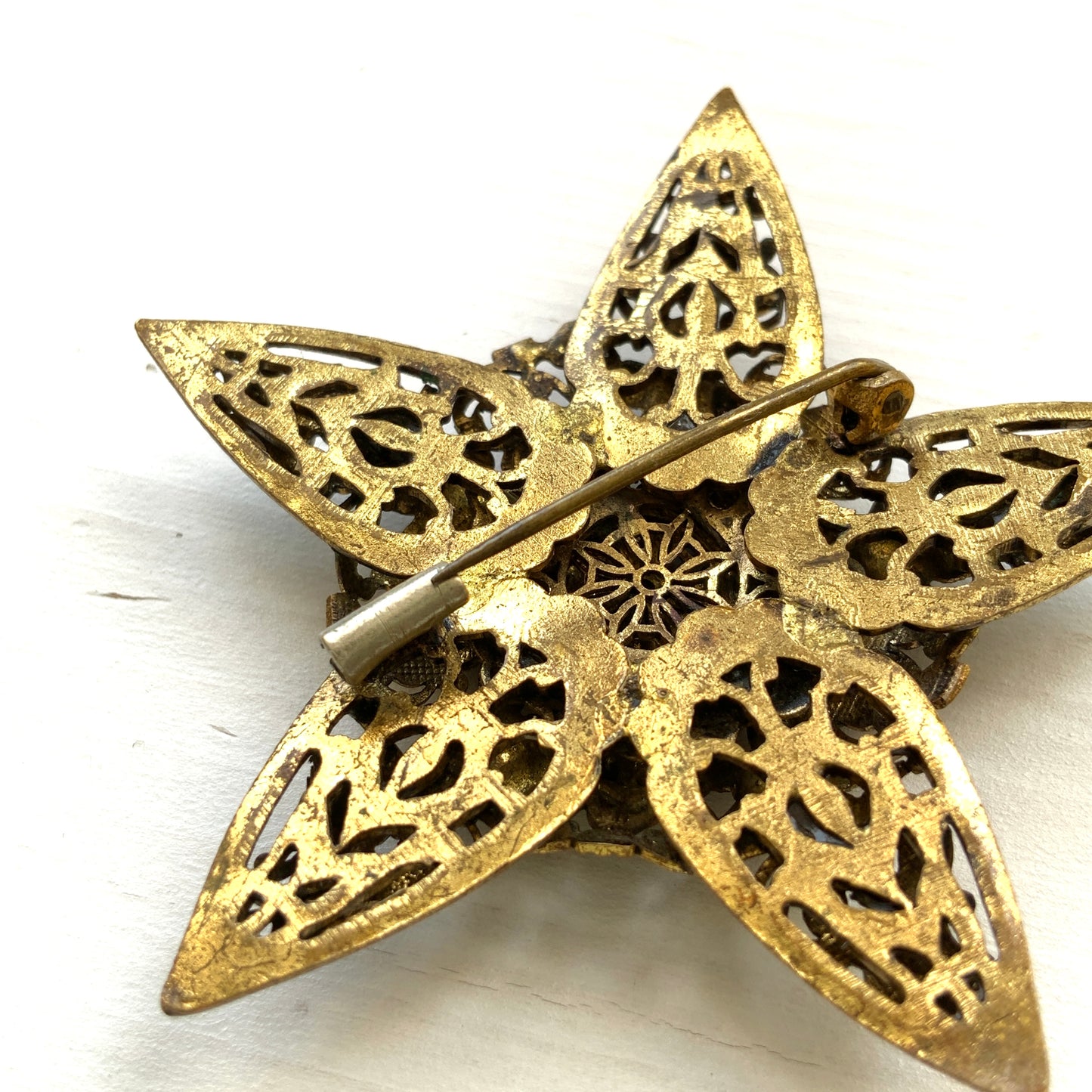A beautiful vintage brooch featuring a star-shaped design crafted in intricate gold-tone filigree, adorned with multicoloured rhinestones. ゴールドトーンの繊細なフィリグリー細工でかたどられた星に、色とりどりのラインストーンがあしらわれたヴィンテージブローチ。