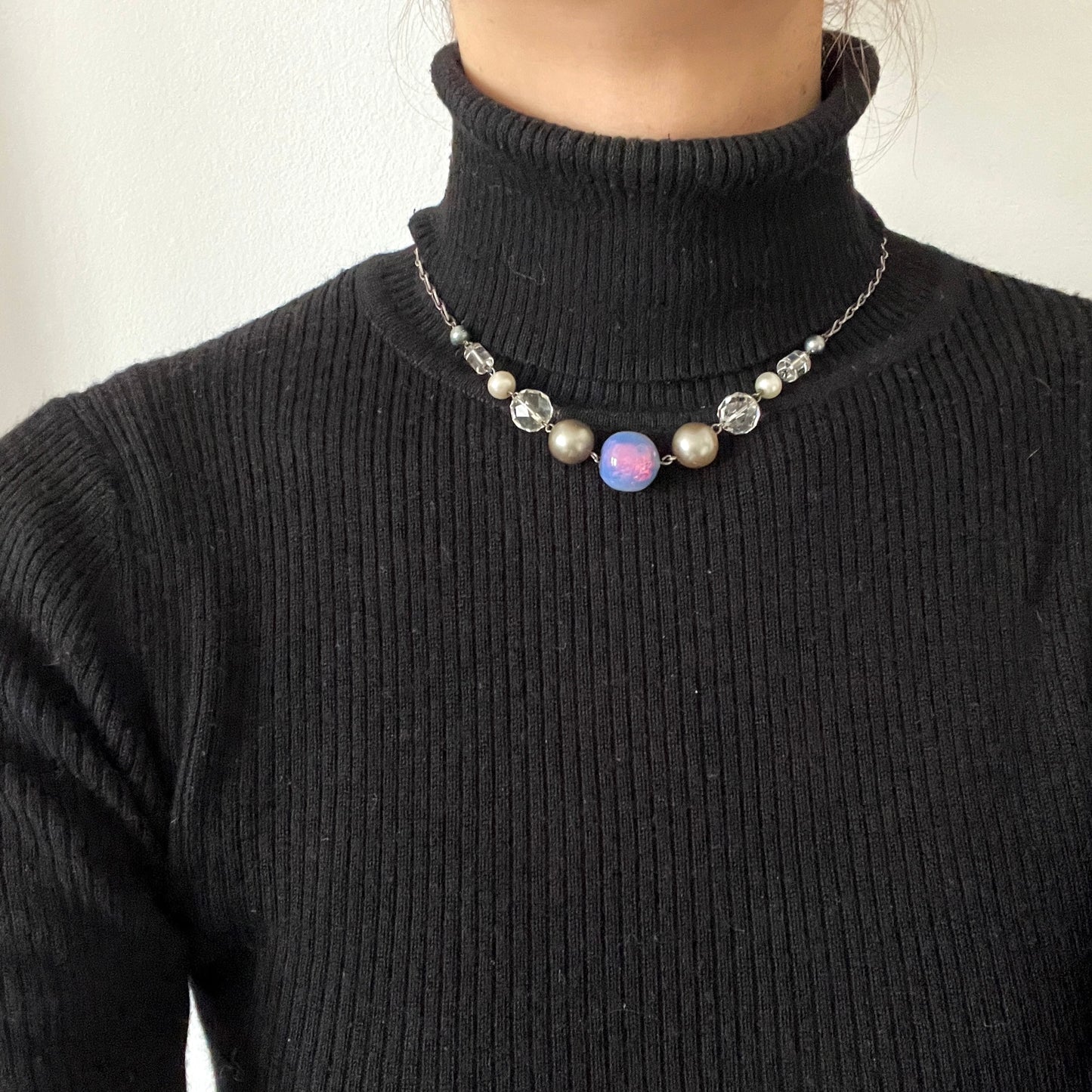 A vintage necklace featuring opalescent glass enclosing pink and violet foil. ピンクやパープルのフォイルを閉じ込めた、オパルセントガラスのヴィンテージネックレス。