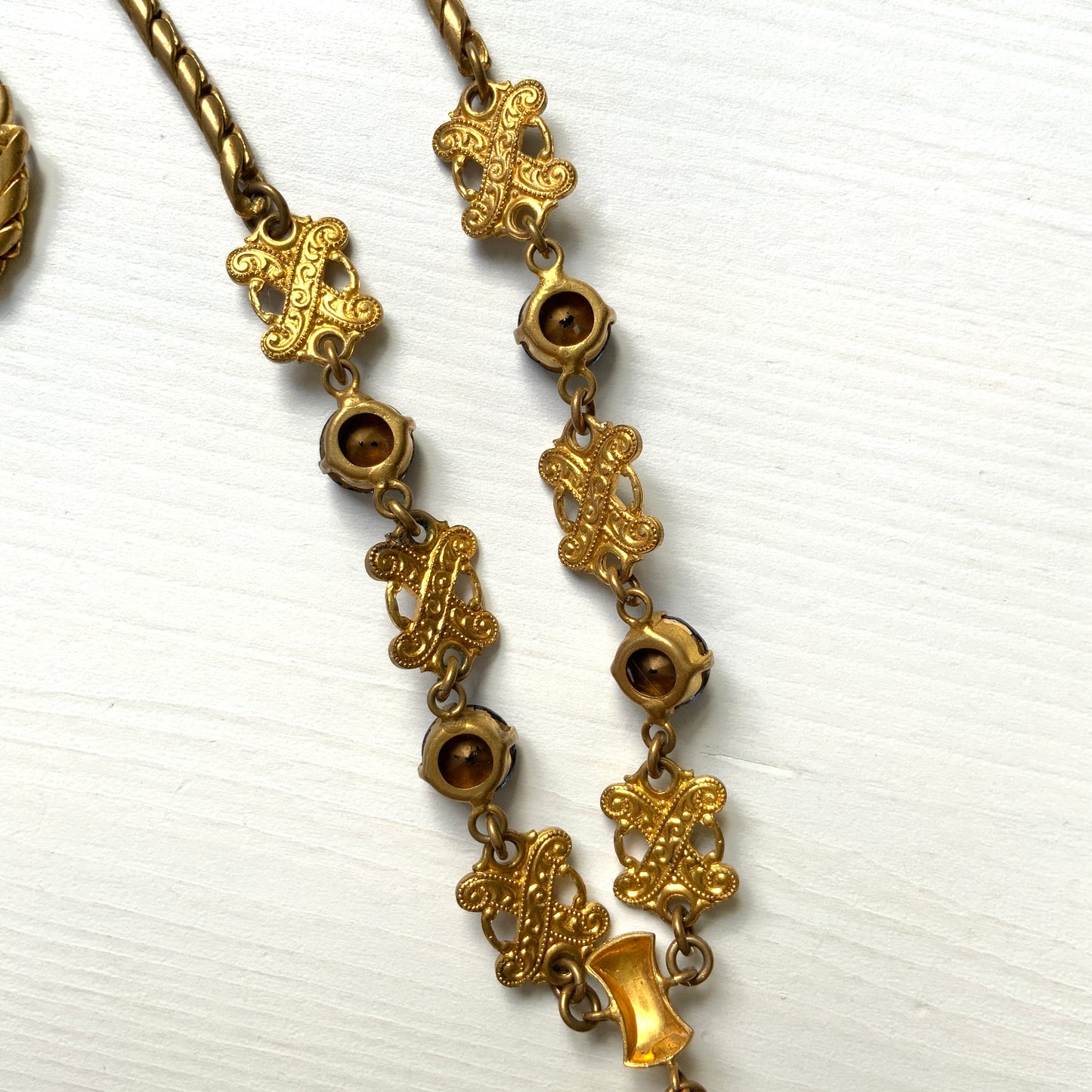 This necklace features a deep ocean-blue oval glass stone set at the center of a beautifully decorated diamond-shaped plate. 深い海のようなディープブルーのオーバルグラスが、美しい装飾を施したダイヤ型プレートの中央にあしらわれたネックレスです。