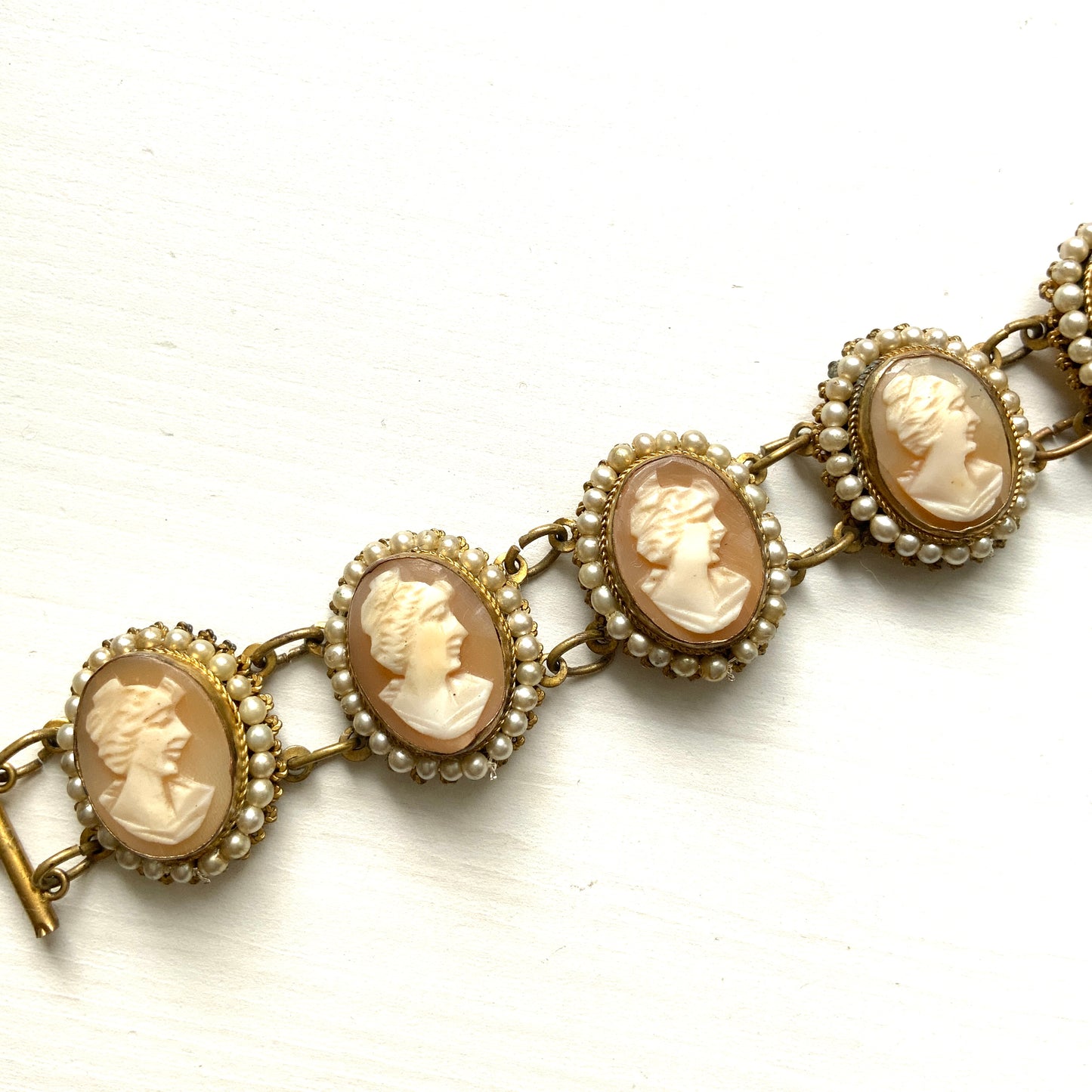 A bracelet lavishly set with seven shell cameos, each delicately framed with tiny glass pearls. 七つのシェルカメオを贅沢に連ねたブレスレット。